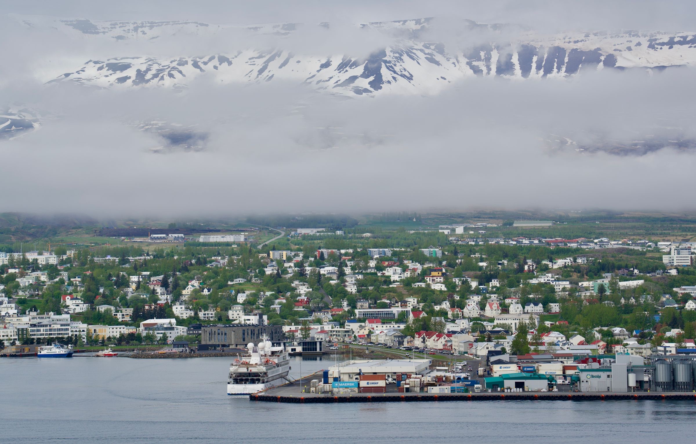 Akureyri's harbour and town seen across the fjord, under misty mountains