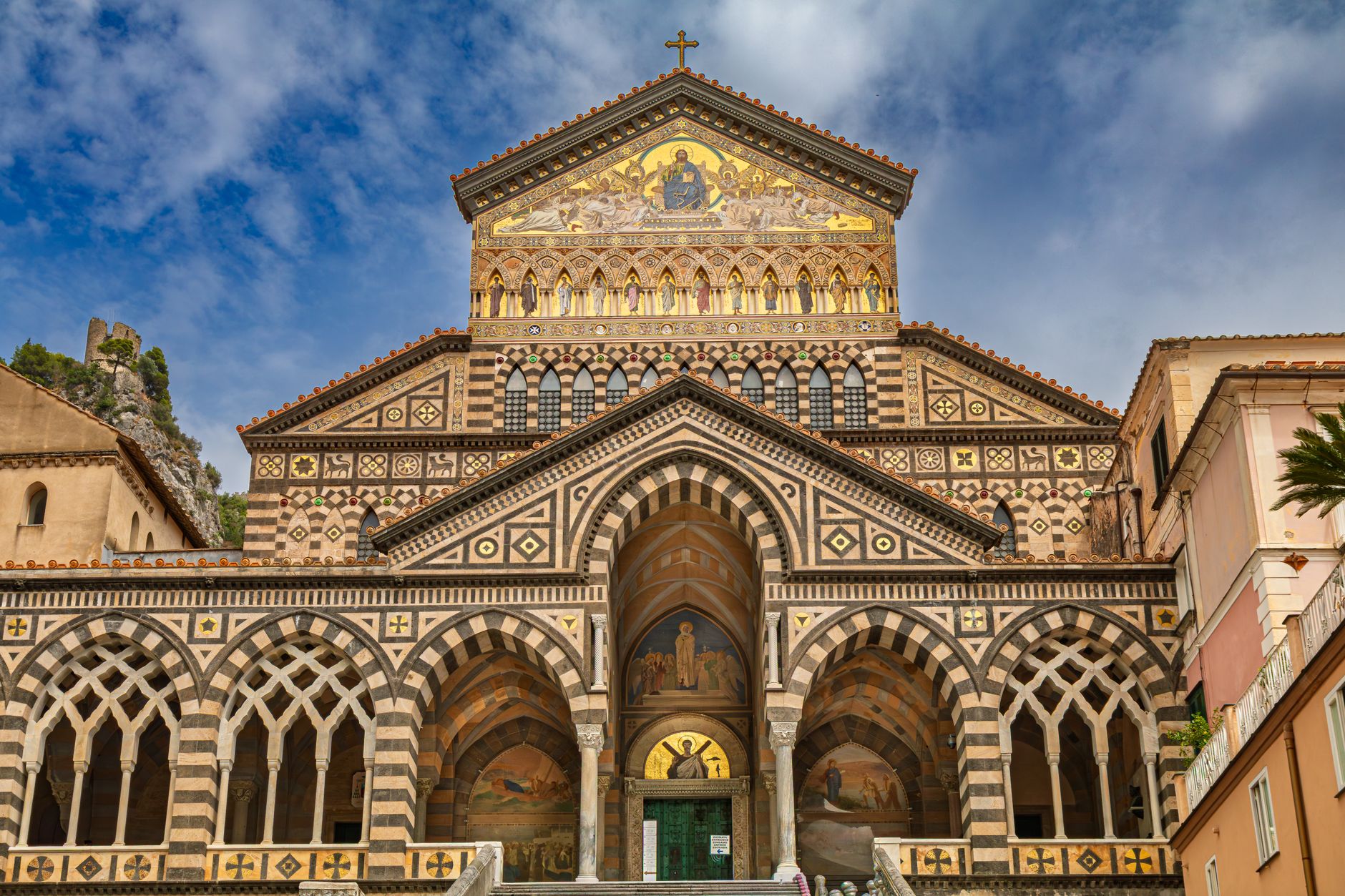 The striped facade of the Duomo di Sant'Andrea in Amalfi, gold mosaic and interlaced arches above a grand staircase