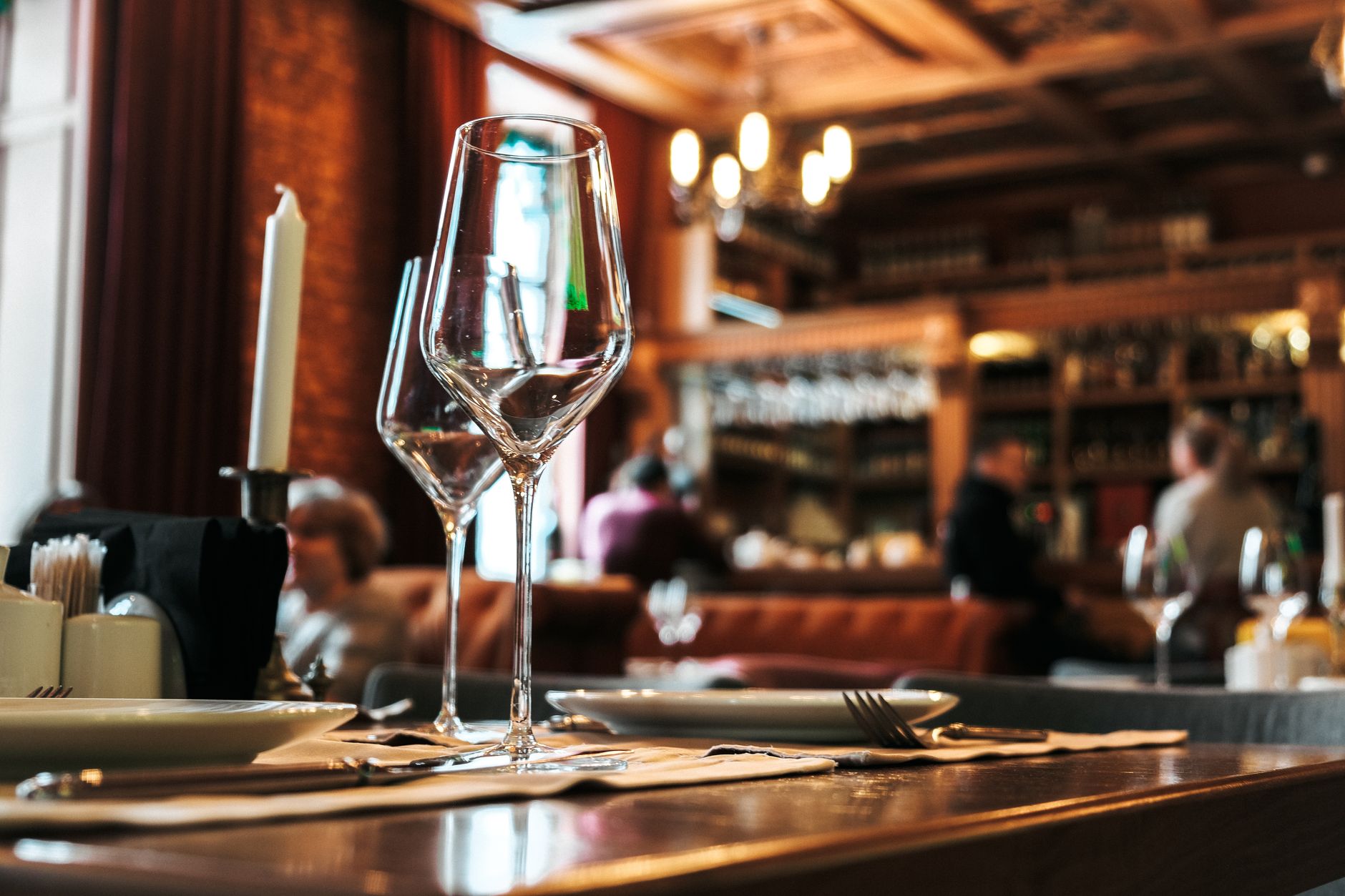 The warm dark wood interior of a traditional Amsterdam brown cafe, bottles and low lamps