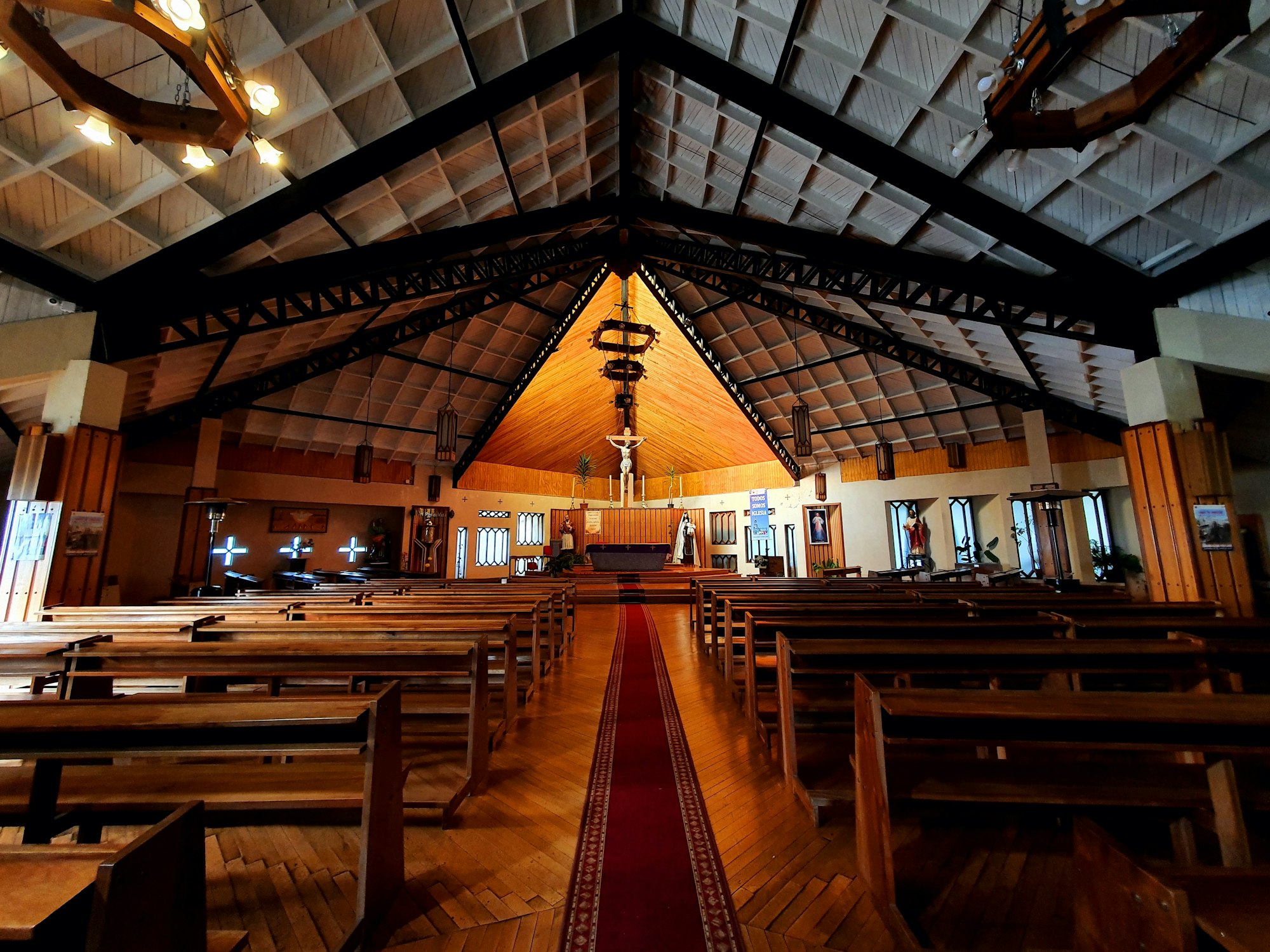 The interior of Ancud's cathedral, rows of wooden pews under a pitched timber roof with a lit altar at the far end
