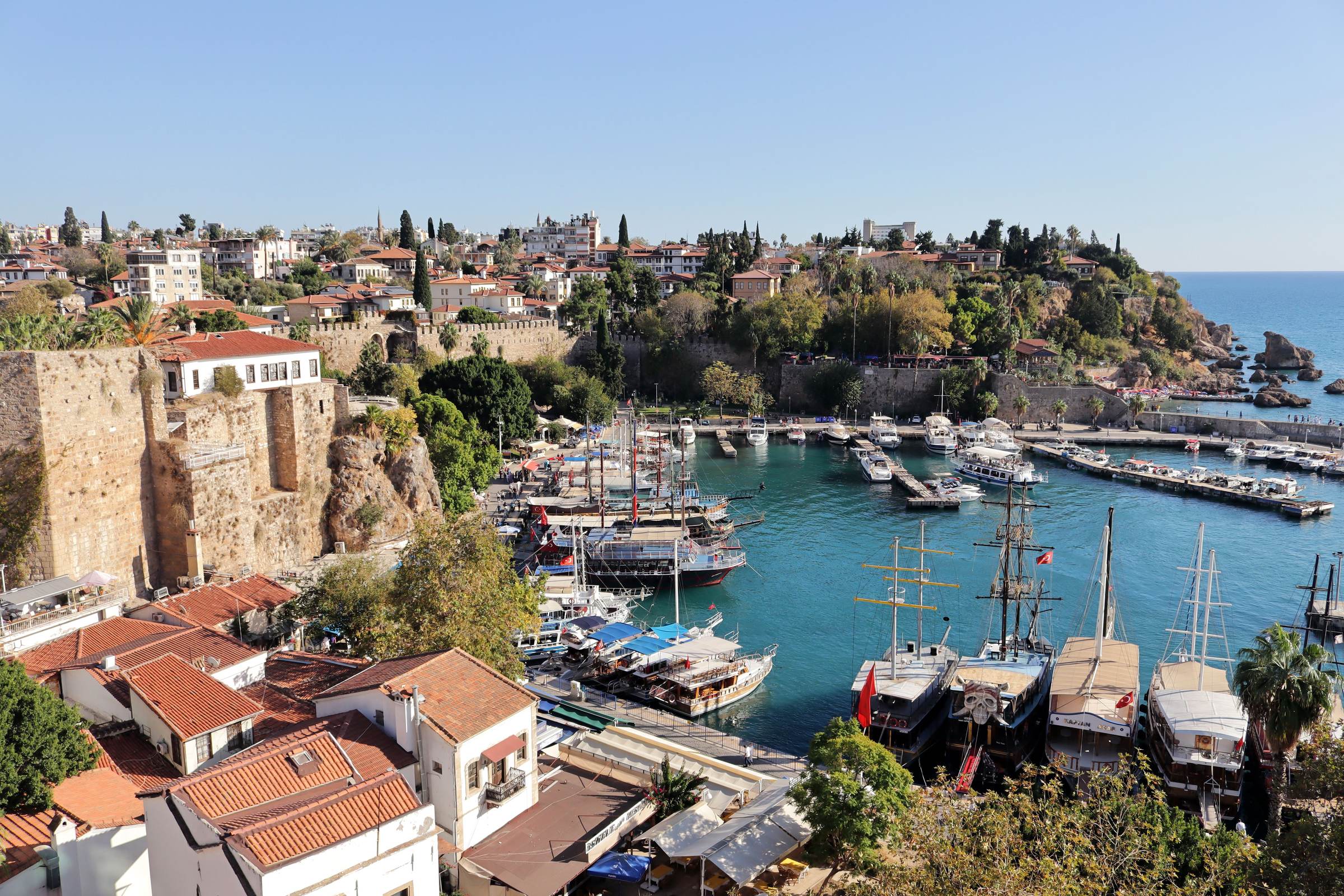 Antalya's old harbour from above, gulets moored inside the sea walls, the red roofs of Kaleiçi on the cliff and the open gulf beyond