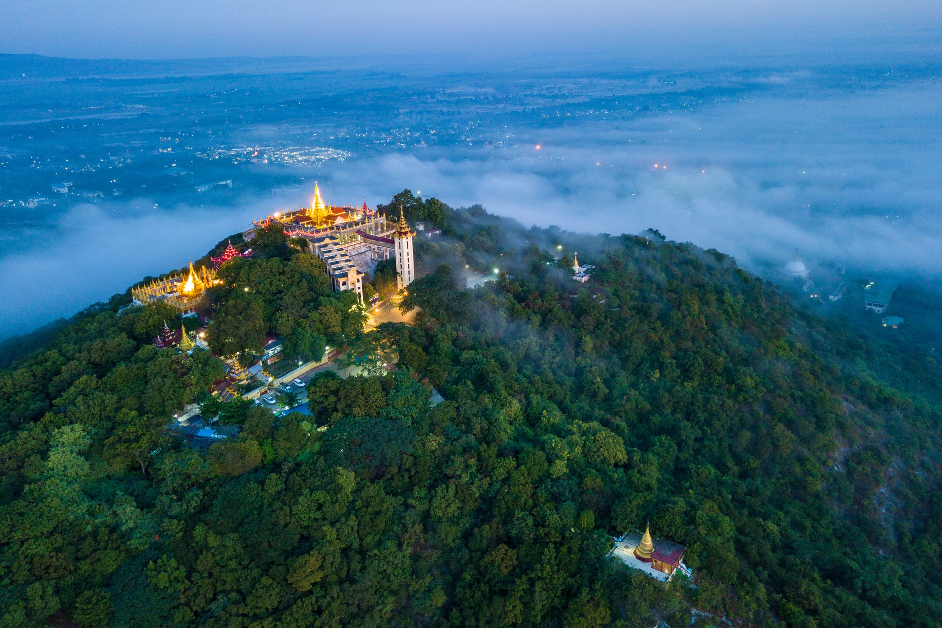 The gilded monastery of Taung Kalat crowning the volcanic plug of Mount Popa above green forest and mist