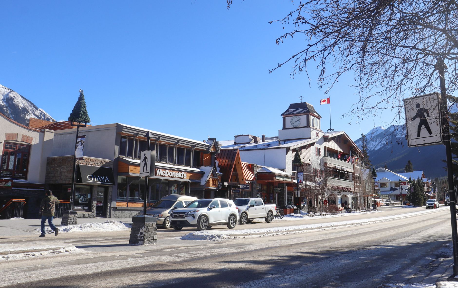 Shops and hotels along Banff Avenue in winter with snow-covered peaks rising beyond the rooftops