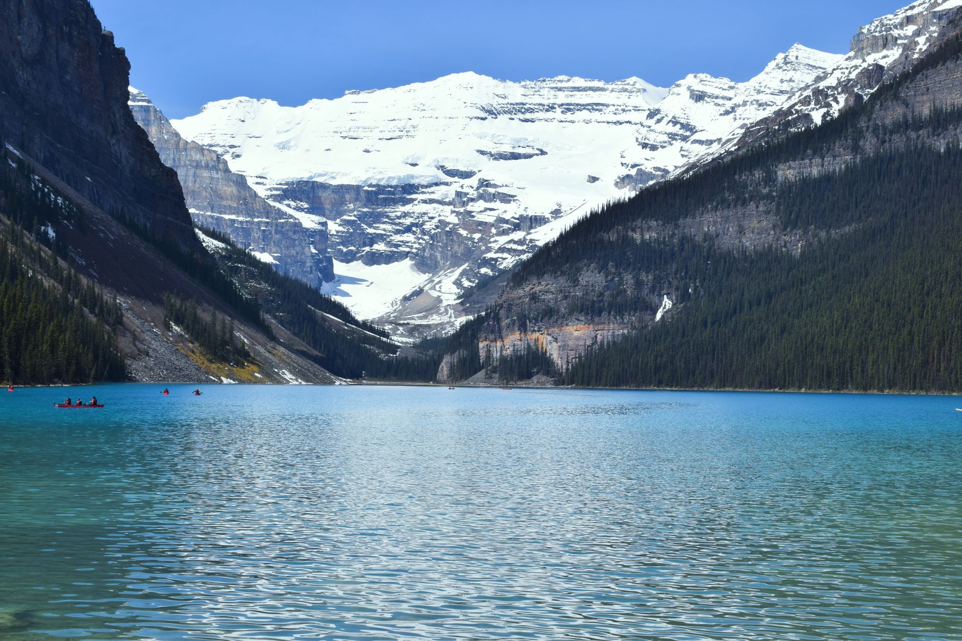 The turquoise water of Lake Louise leading to the Victoria Glacier hanging between steep mountain walls