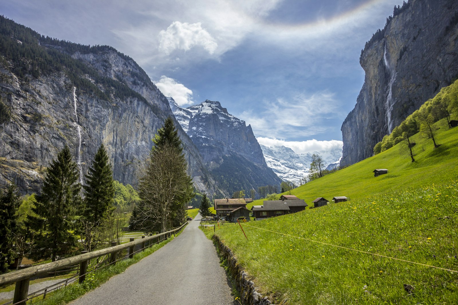 A quiet lane through green meadows under the cliffs of the Lauterbrunnen valley