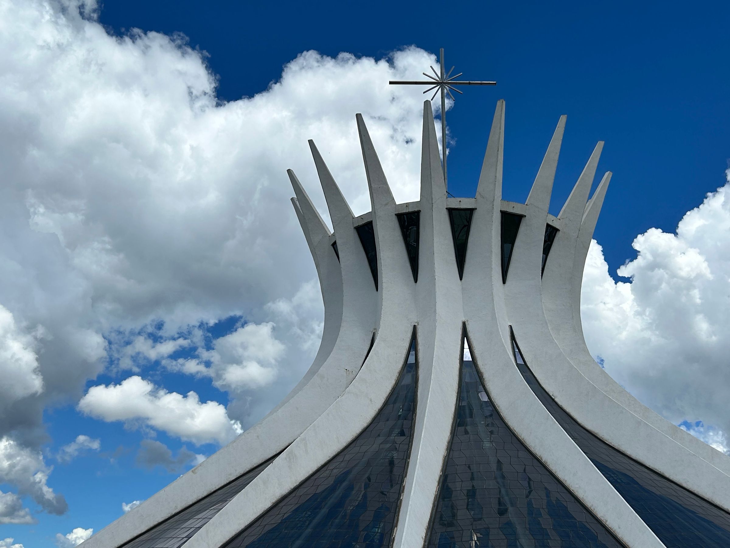 The sixteen white concrete columns of the Cathedral of Brasília flaring open to the sky beneath a cross