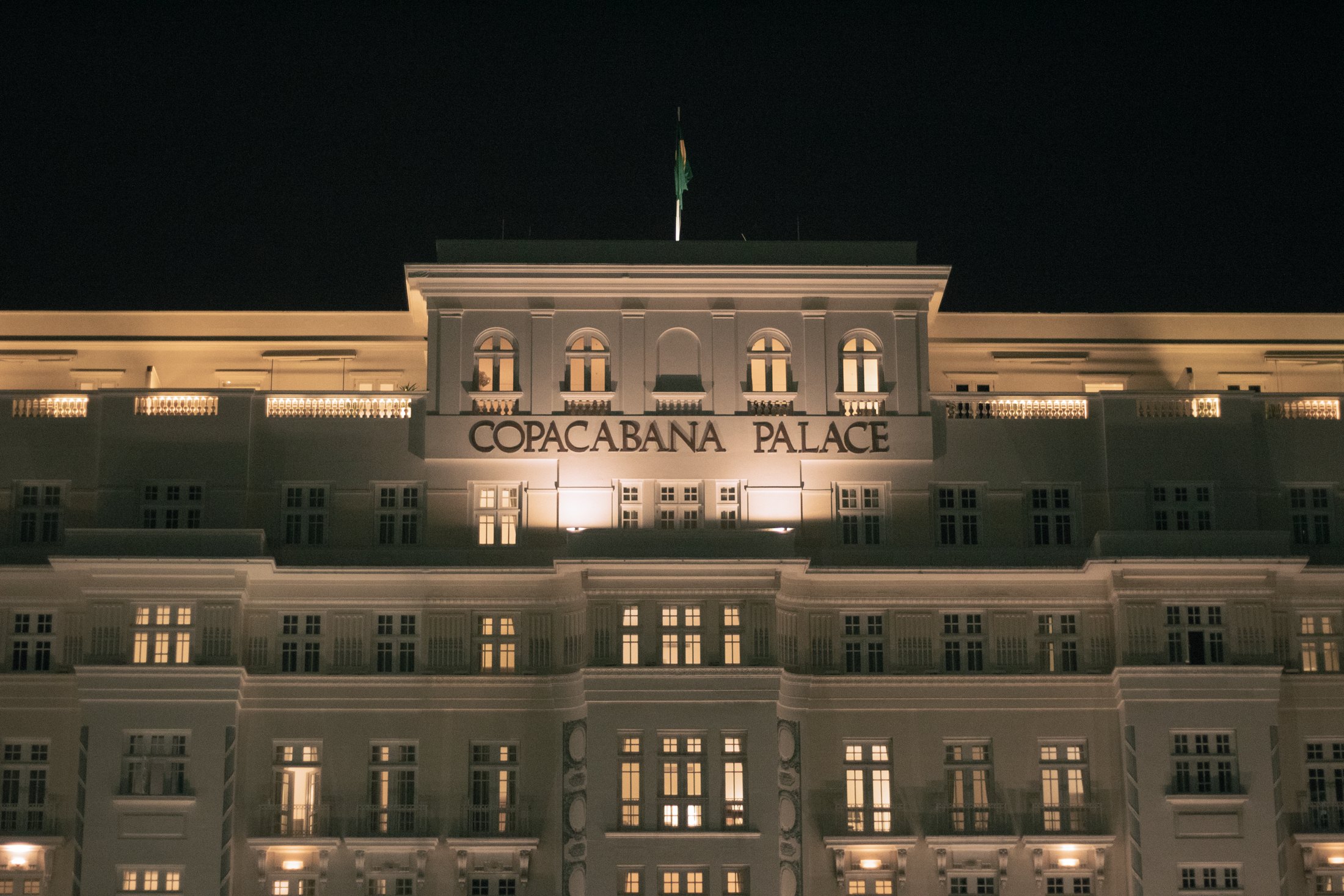 The floodlit white facade of the Copacabana Palace hotel at night, its name across the parapet