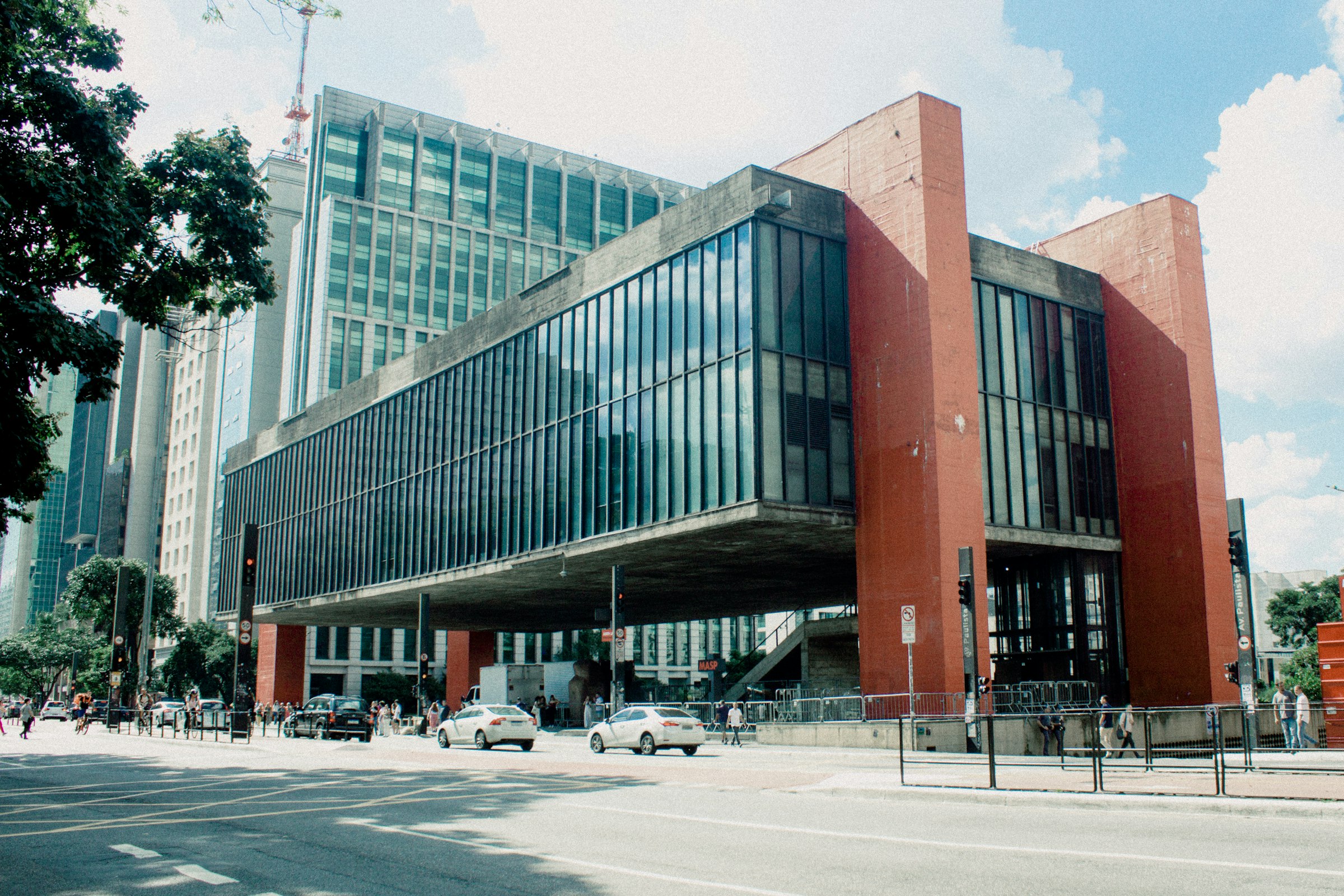 The glass-and-concrete box of MASP held up by its red beams above the open public plaza on Avenida Paulista