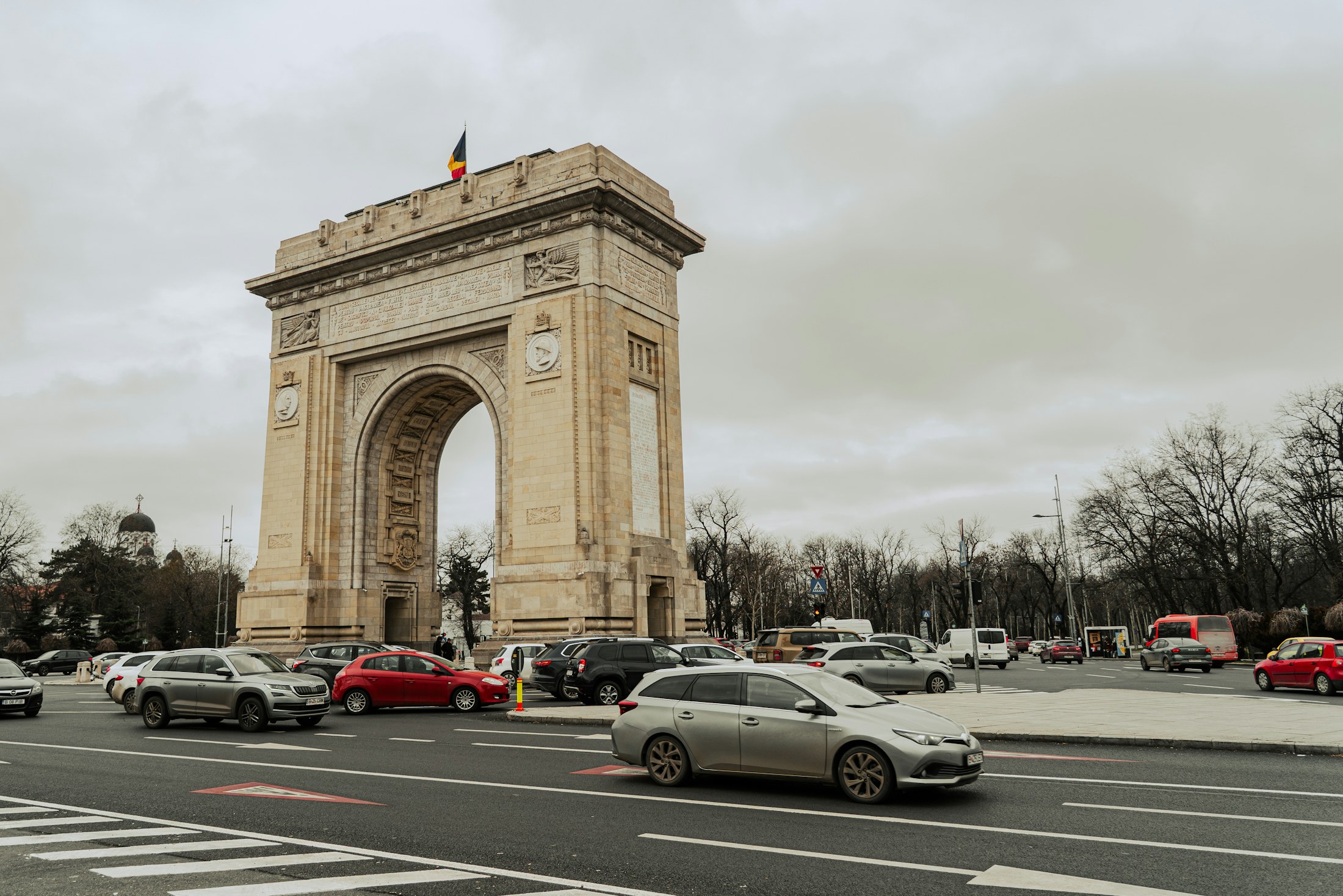 The Arch of Triumph in Bucharest with traffic passing on the Kiseleff axis