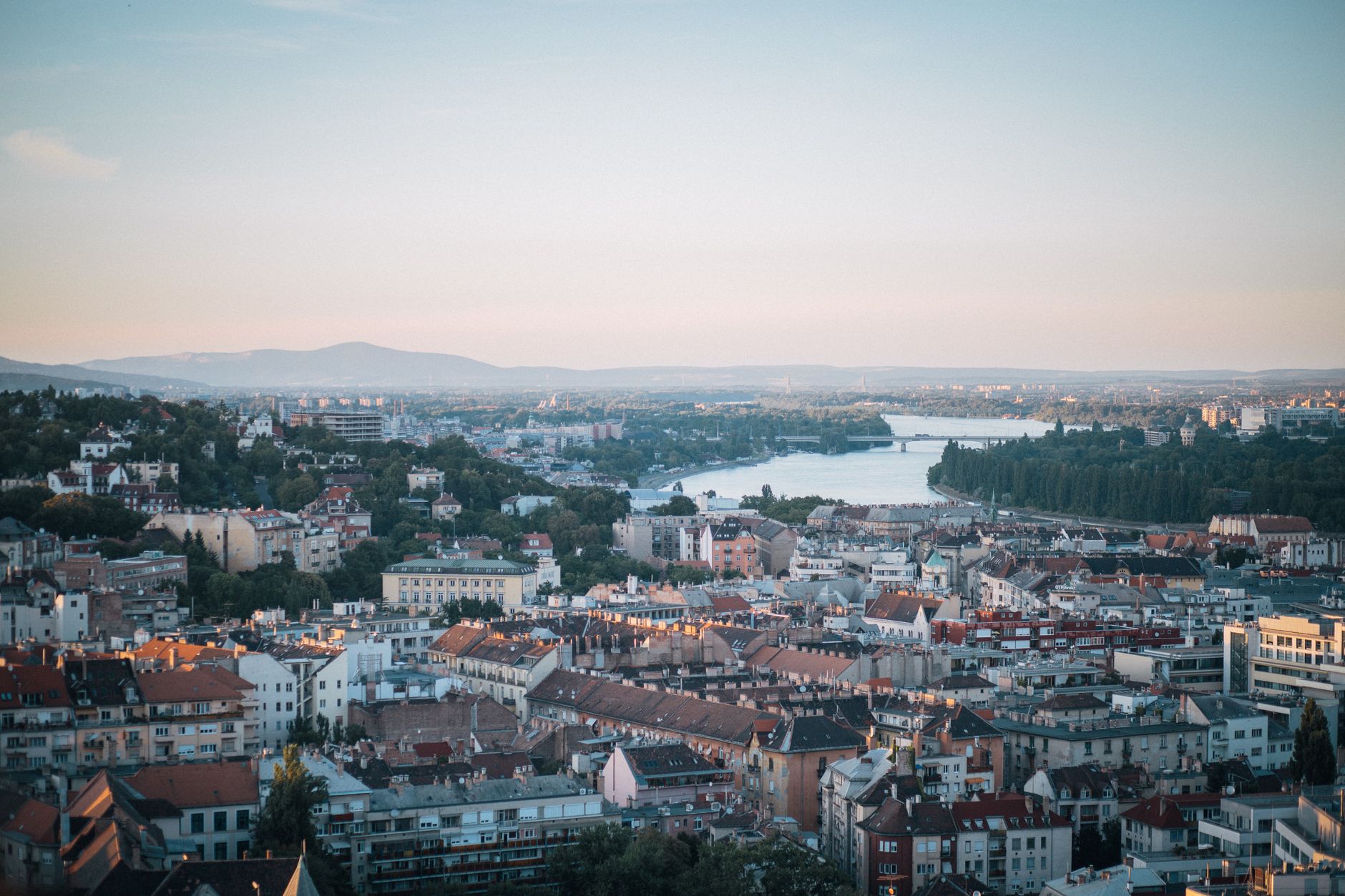 A high view over Budapest rooftops toward the Danube at dusk