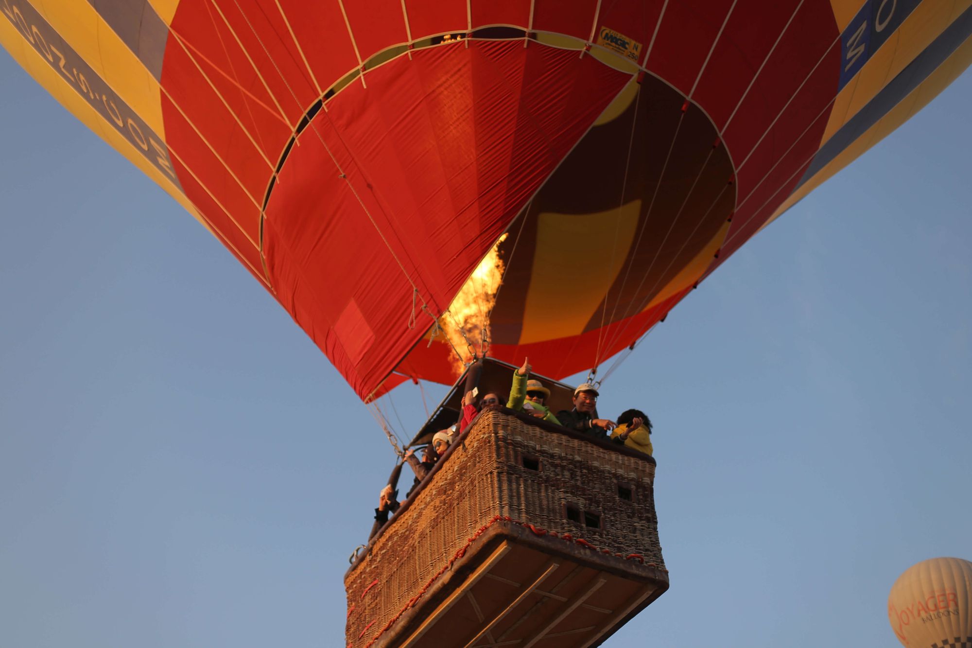 A hot air balloon firing its burner with passengers in the basket over Cappadocia
