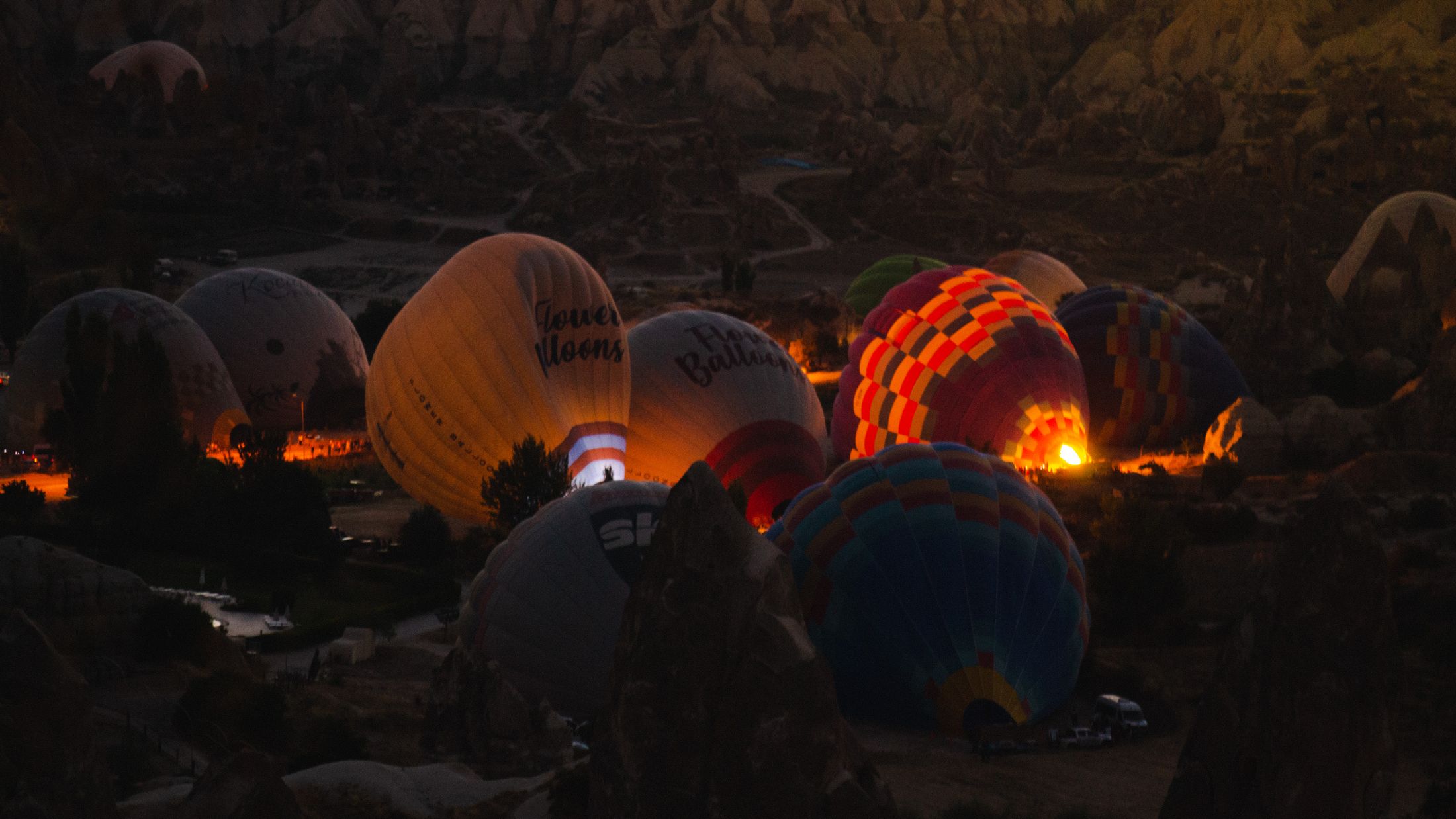 Hot air balloons being inflated and glowing on the ground before dawn in Cappadocia