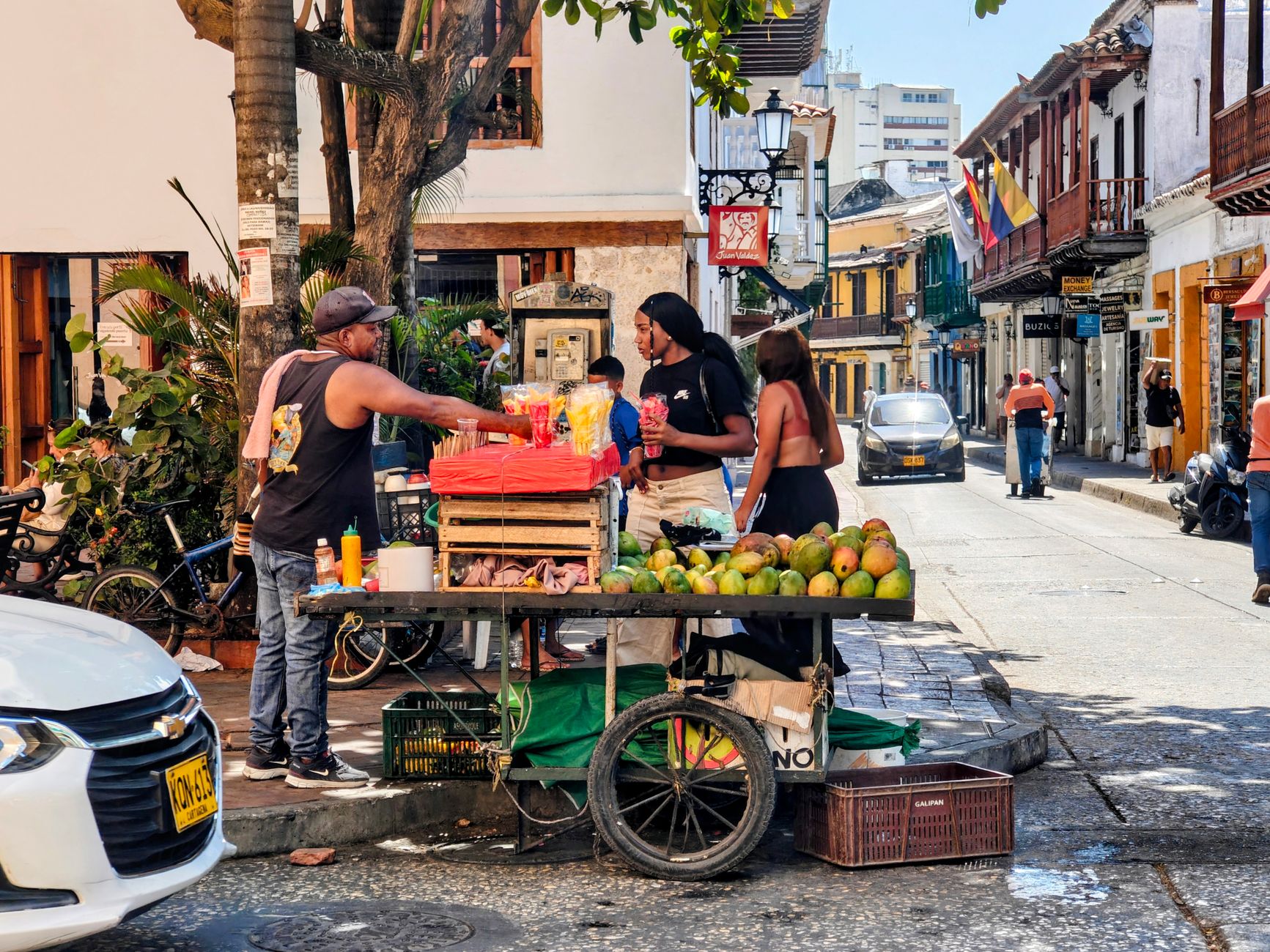 A fruit cart piled with mangoes and tropical fruit in a street of the walled city
