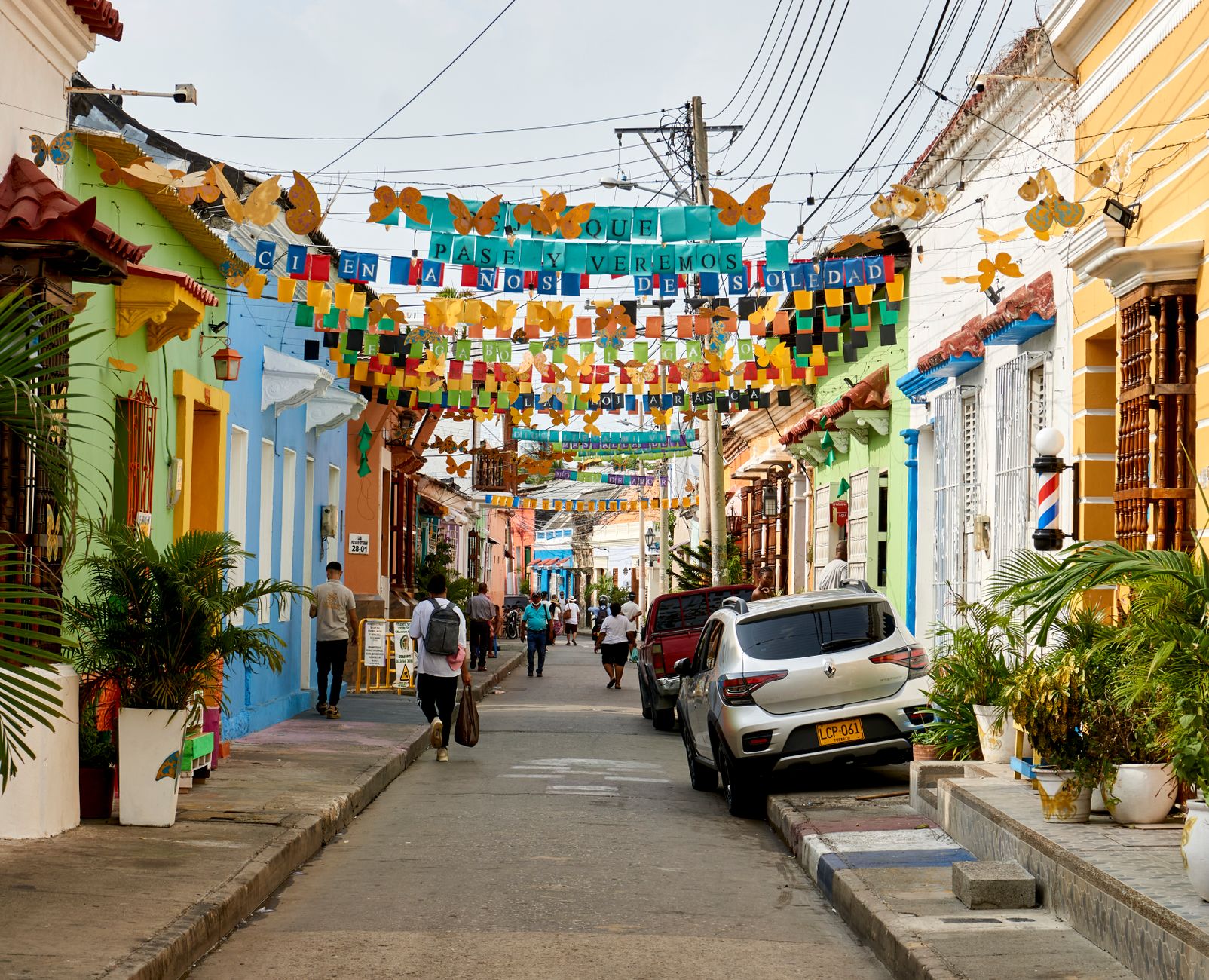 A narrow street in Getsemani hung with letter banners and paper butterflies, people walking beneath