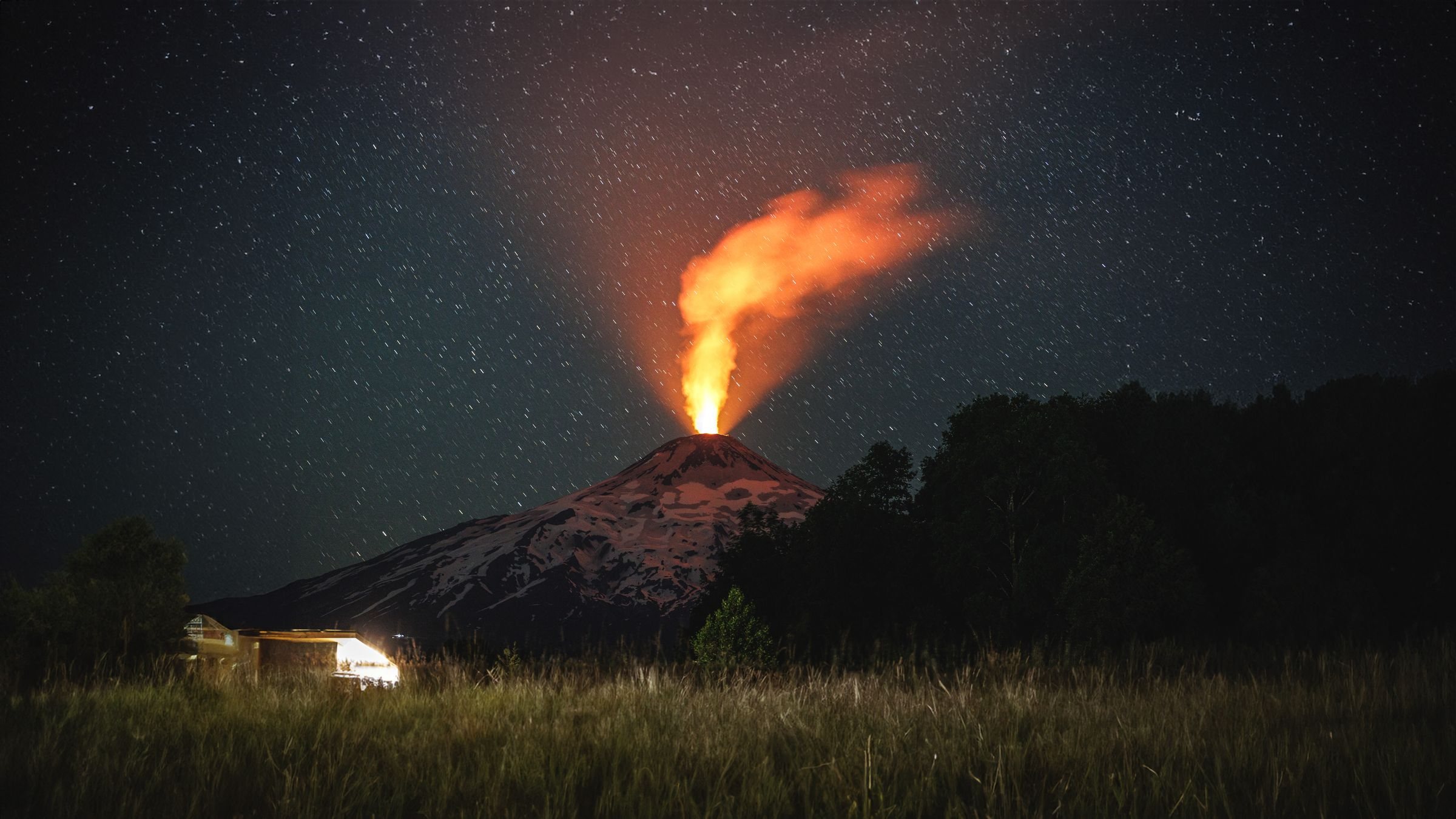 Villarrica volcano erupting at night, a column of glowing lava above the crater under a starry sky