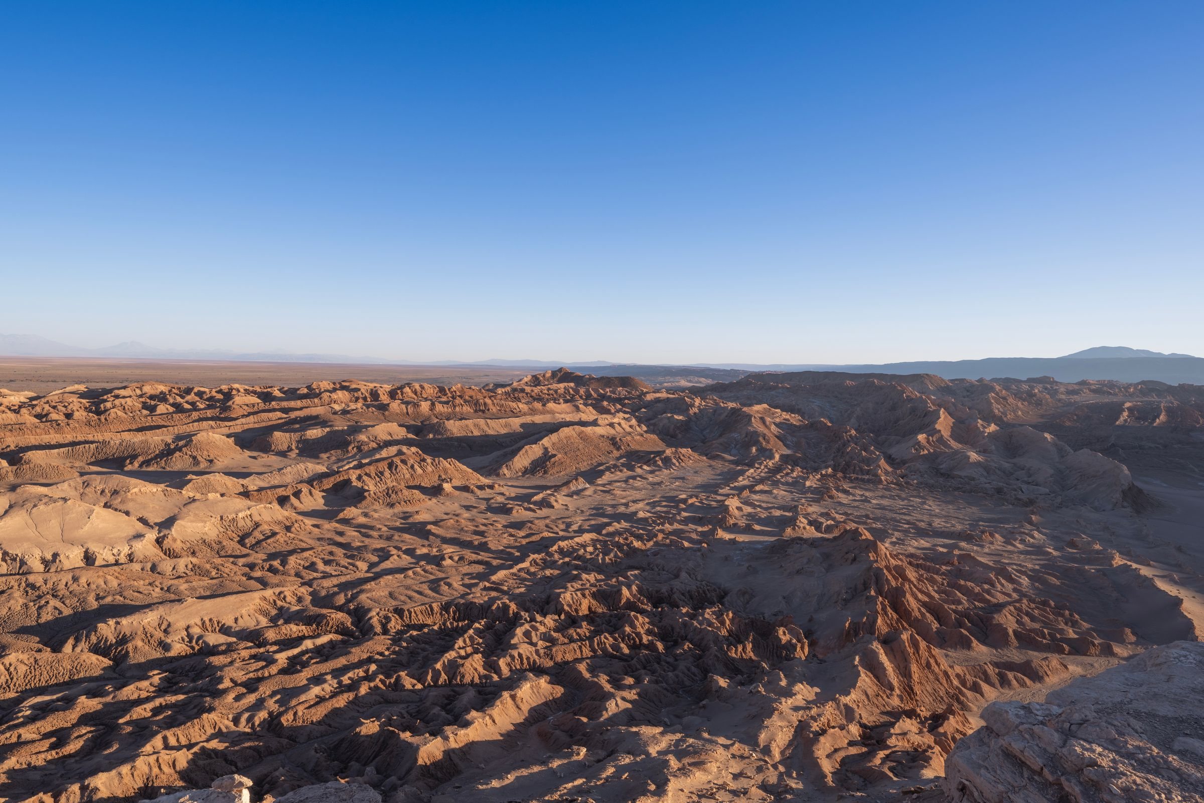 The Valle de la Luna from the air, ridges of salt-crusted rock and sand under a low sun in the Atacama Desert