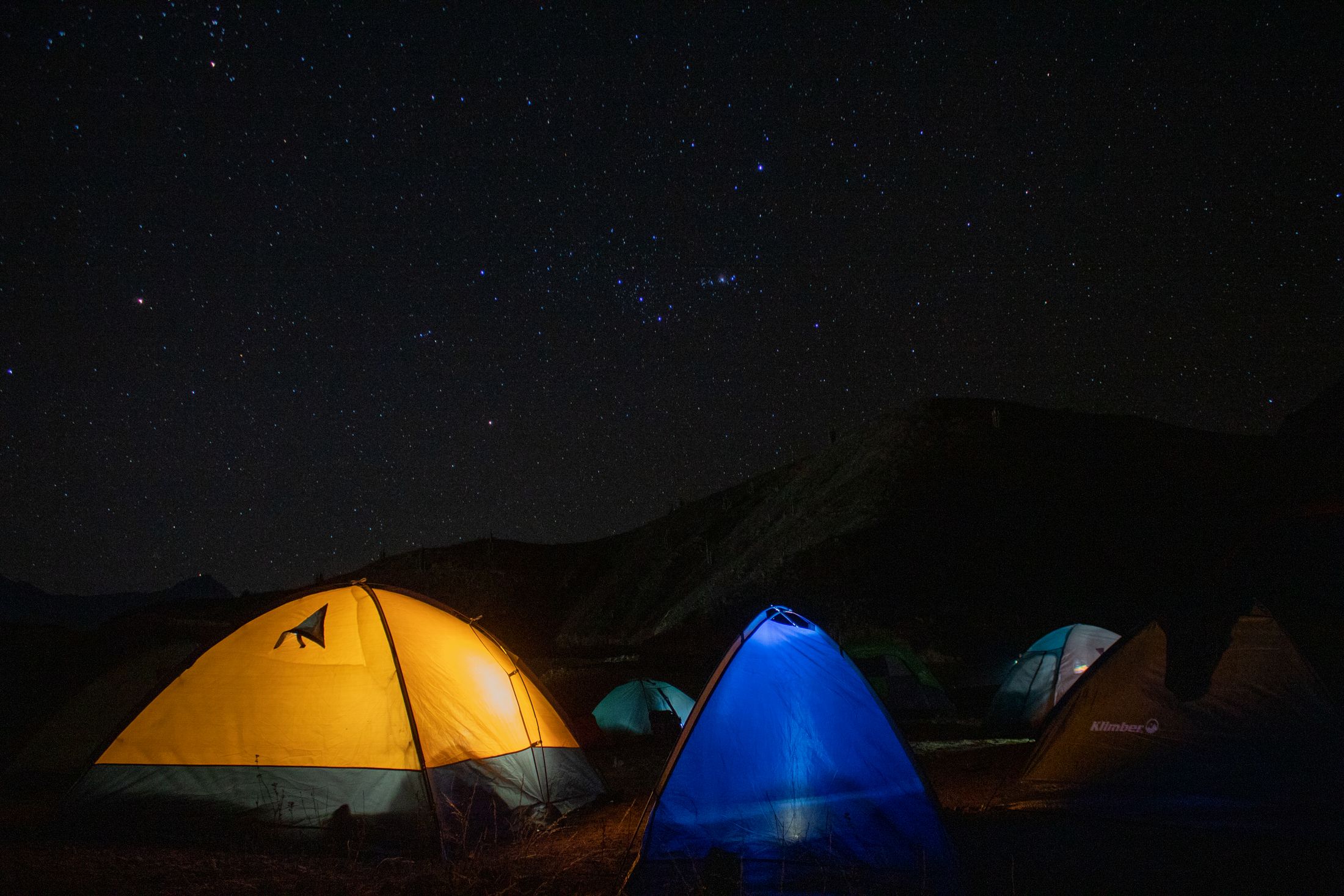 Tents glowing under a starry night sky at a camp in the Peruvian Andes