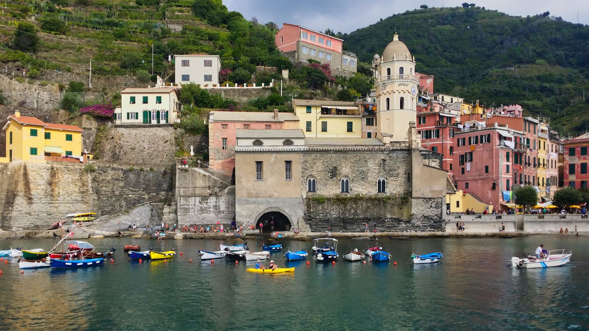 The harbour of Vernazza in the Cinque Terre, coloured houses and a church around fishing boats on turquoise water