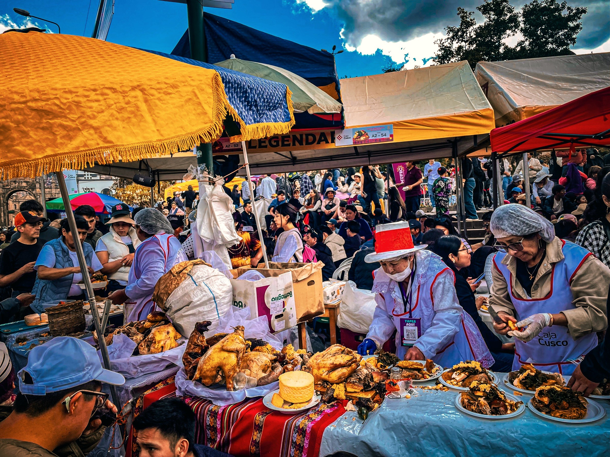 Festival food stalls in Cusco serving chiri uchu, women in white aprons plating roasted hen, guinea pig and cheese for the crowd