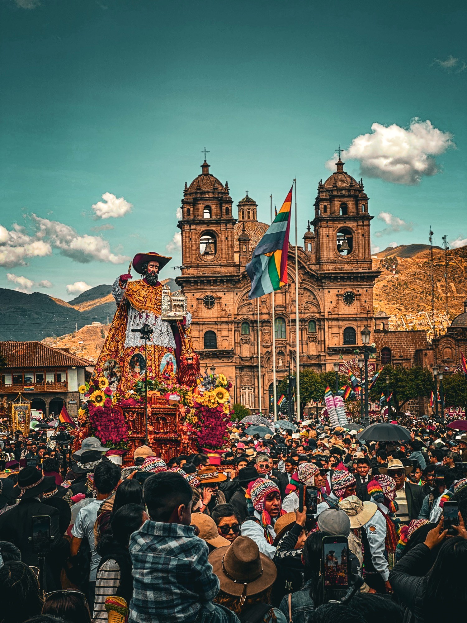 The image of San Jeronimo on his ornate gold and silver anda, banked in roses and sunflowers, carried through the crowd with La Compañía church behind