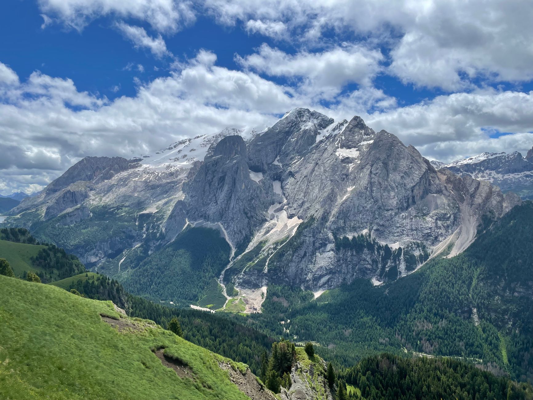 The Marmolada massif across a green ridge, its rock face streaked with the last of the summer snow
