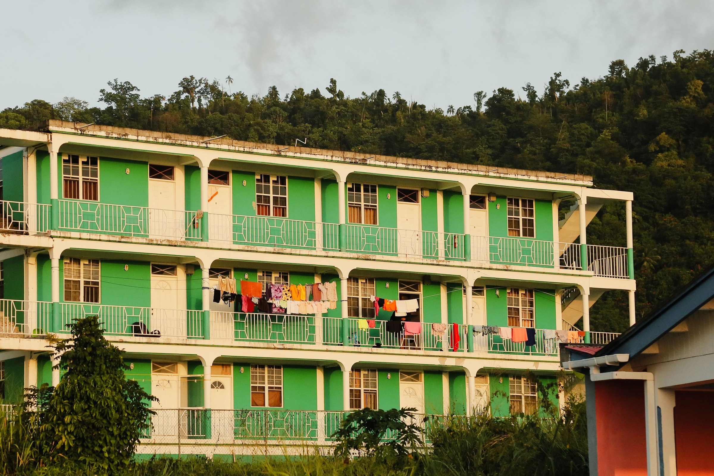A green and cream apartment building with washing hung along its balconies in Portsmouth, Dominica