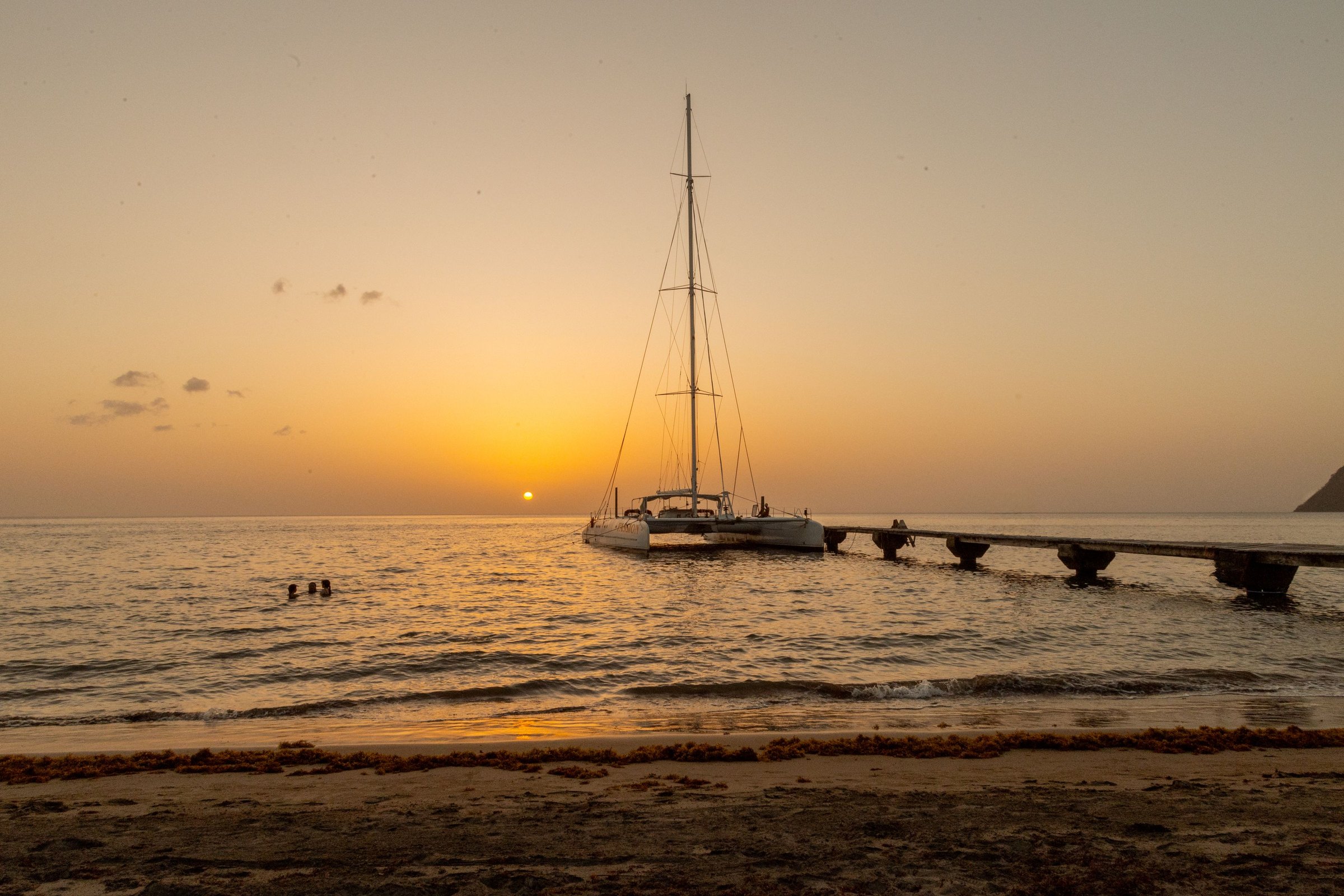 A yacht moored off a pier at sunset on the leeward coast of Dominica