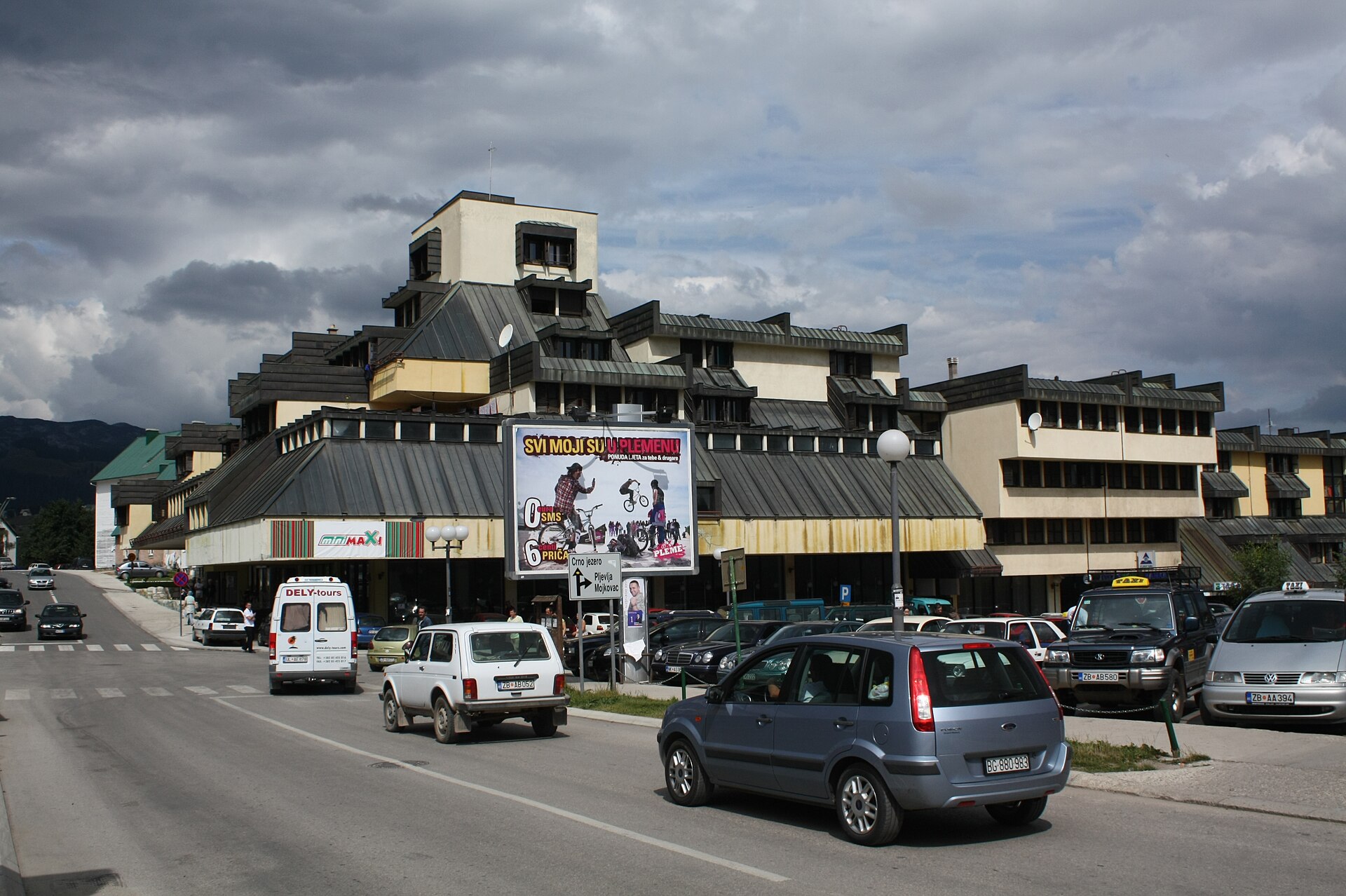 The centre of Žabljak, Montenegro: a stepped modernist block with a shop parade at street level and traffic on the through road