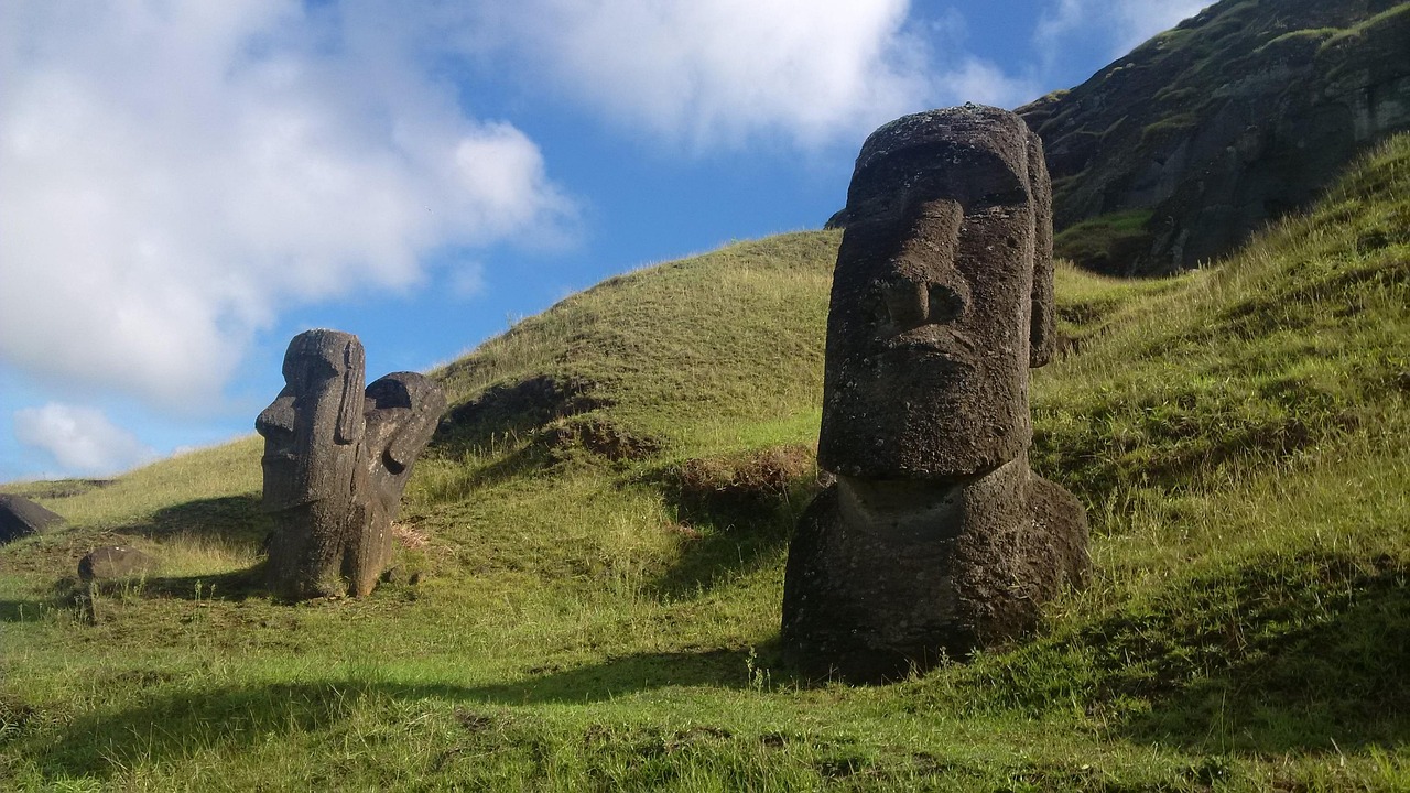 Two moai standing in grass on the green slope of the Rano Raraku quarry