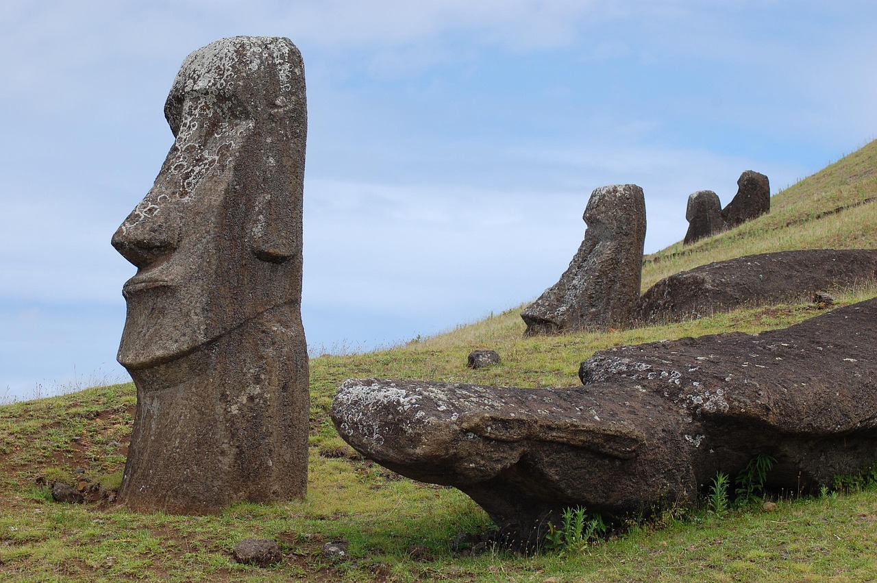 A large moai standing on the grassy slope of Rano Raraku beside a fallen statue