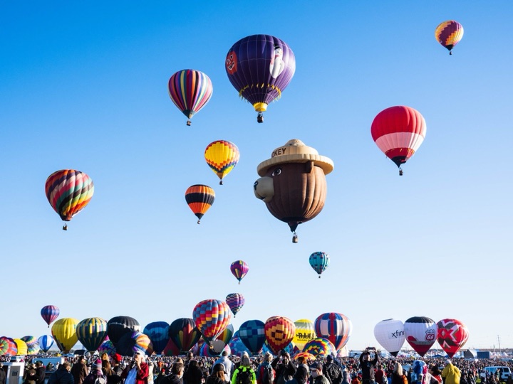 Hot air balloons rising over and inflating on the launch field at Balloon Fiesta Park, Albuquerque