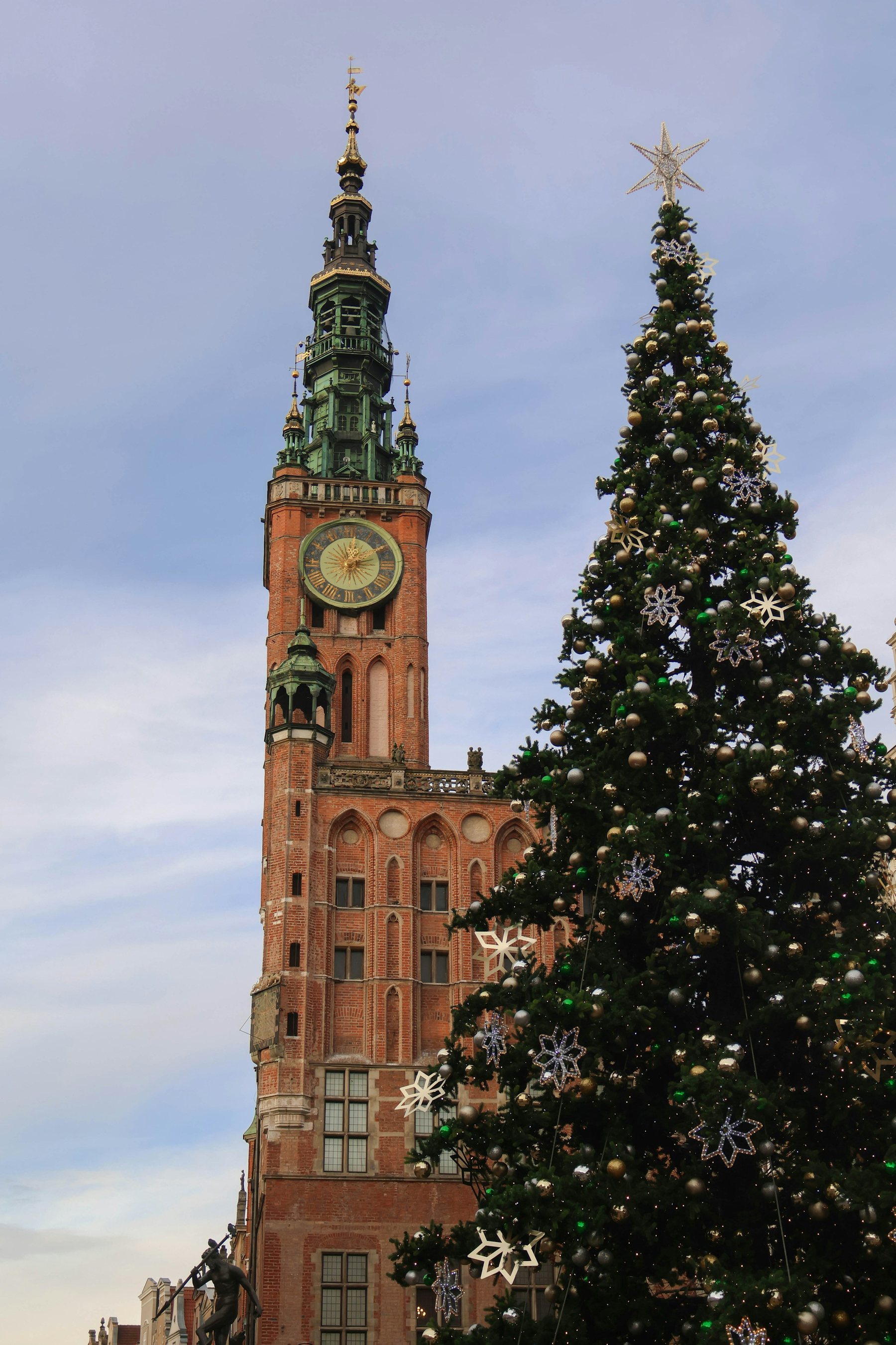 A large Christmas tree in front of a tall brick building in Gdańsk