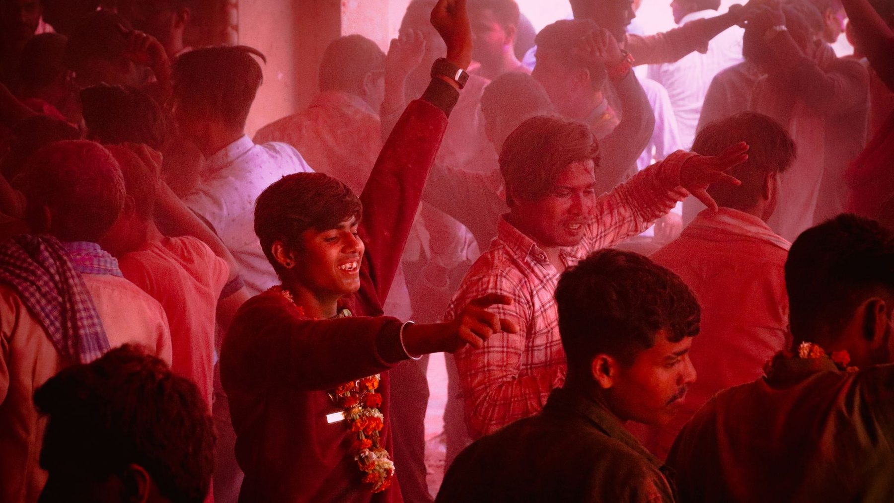 Dancing in a crowd at Barsana during Holi, powder rising over the heads
