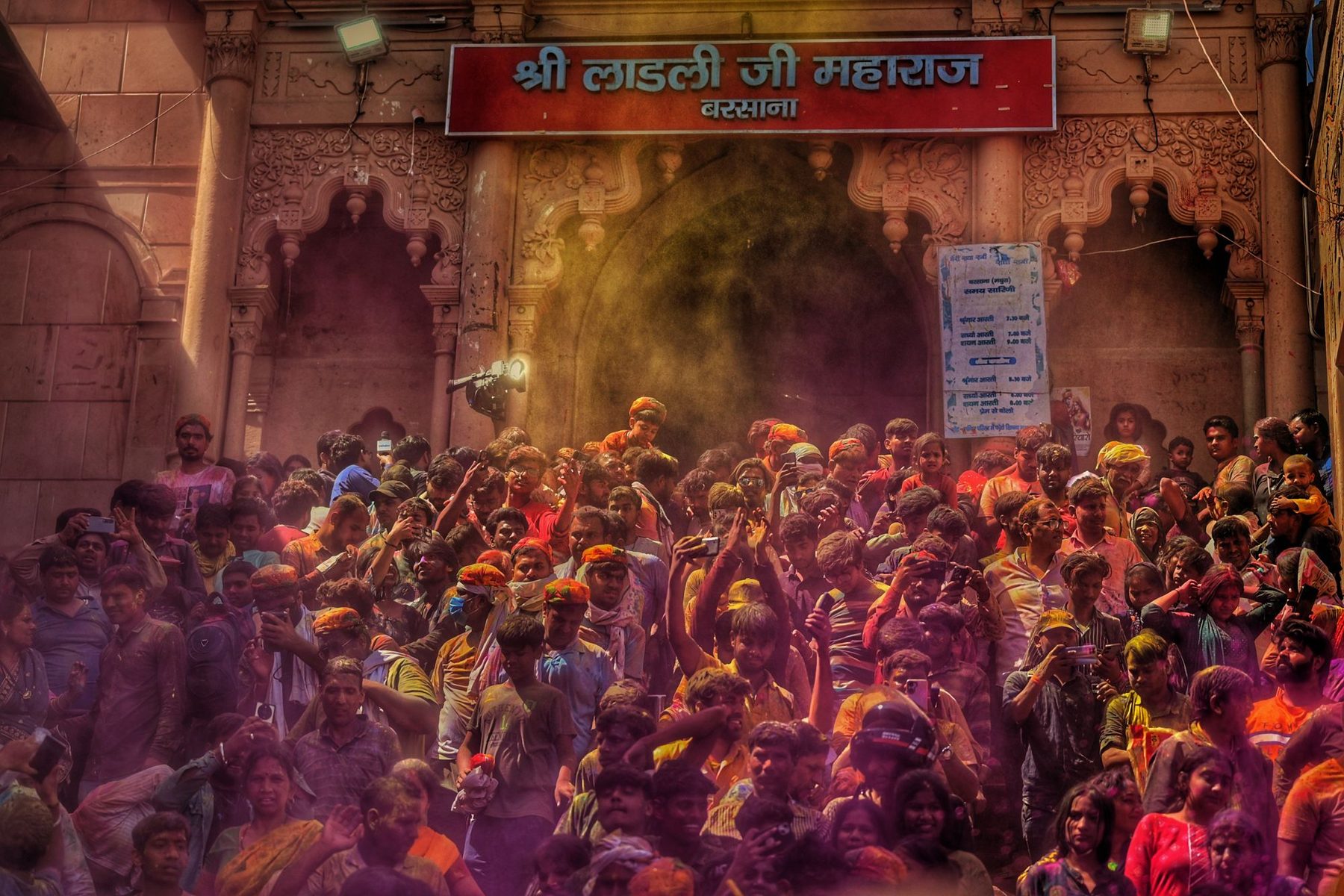 The courtyard of the Ladli Ji temple in Barsana packed with a crowd under a cloud of coloured powder