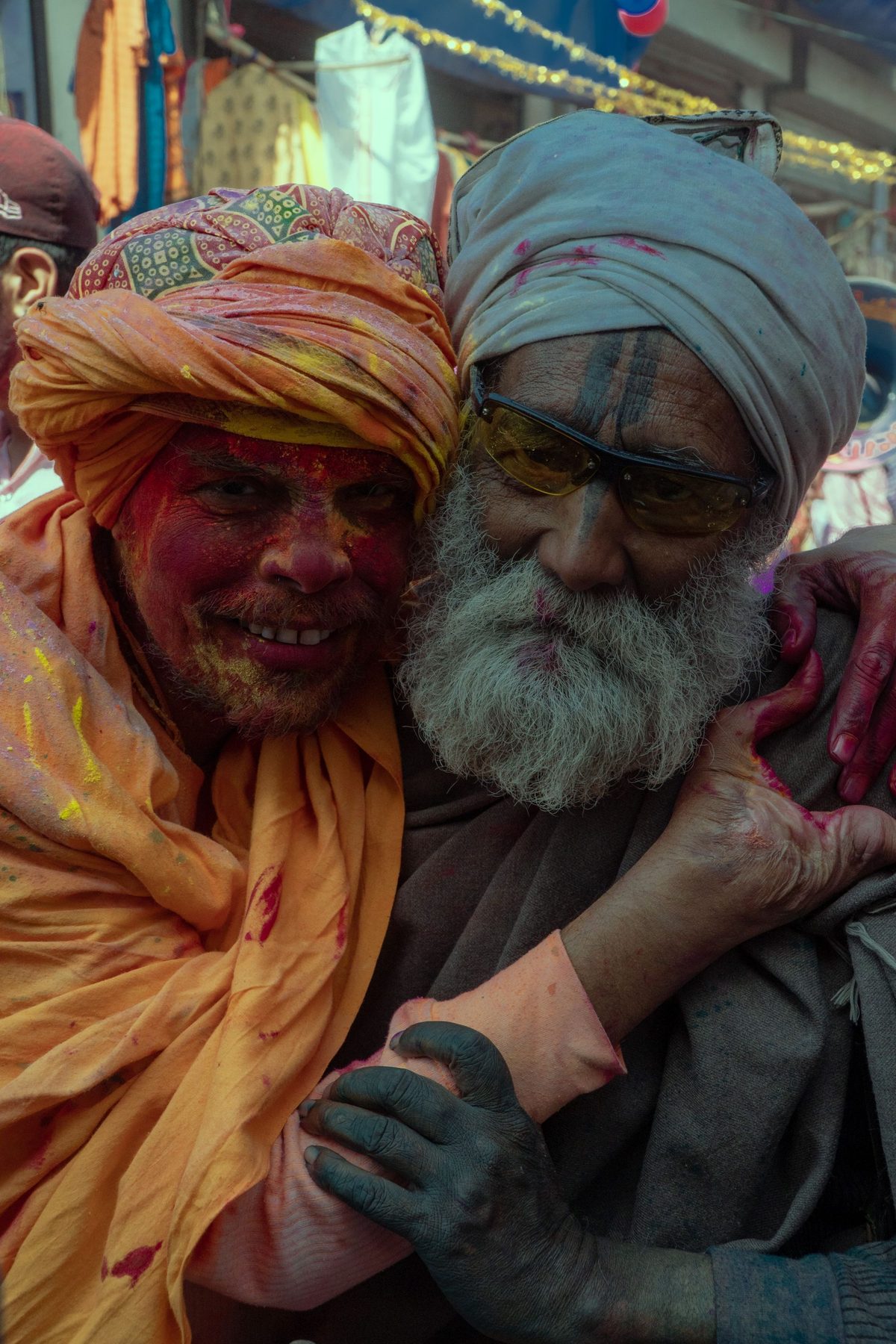 A man in Mathura in traditional dress, his face and clothes covered in pink and orange colour