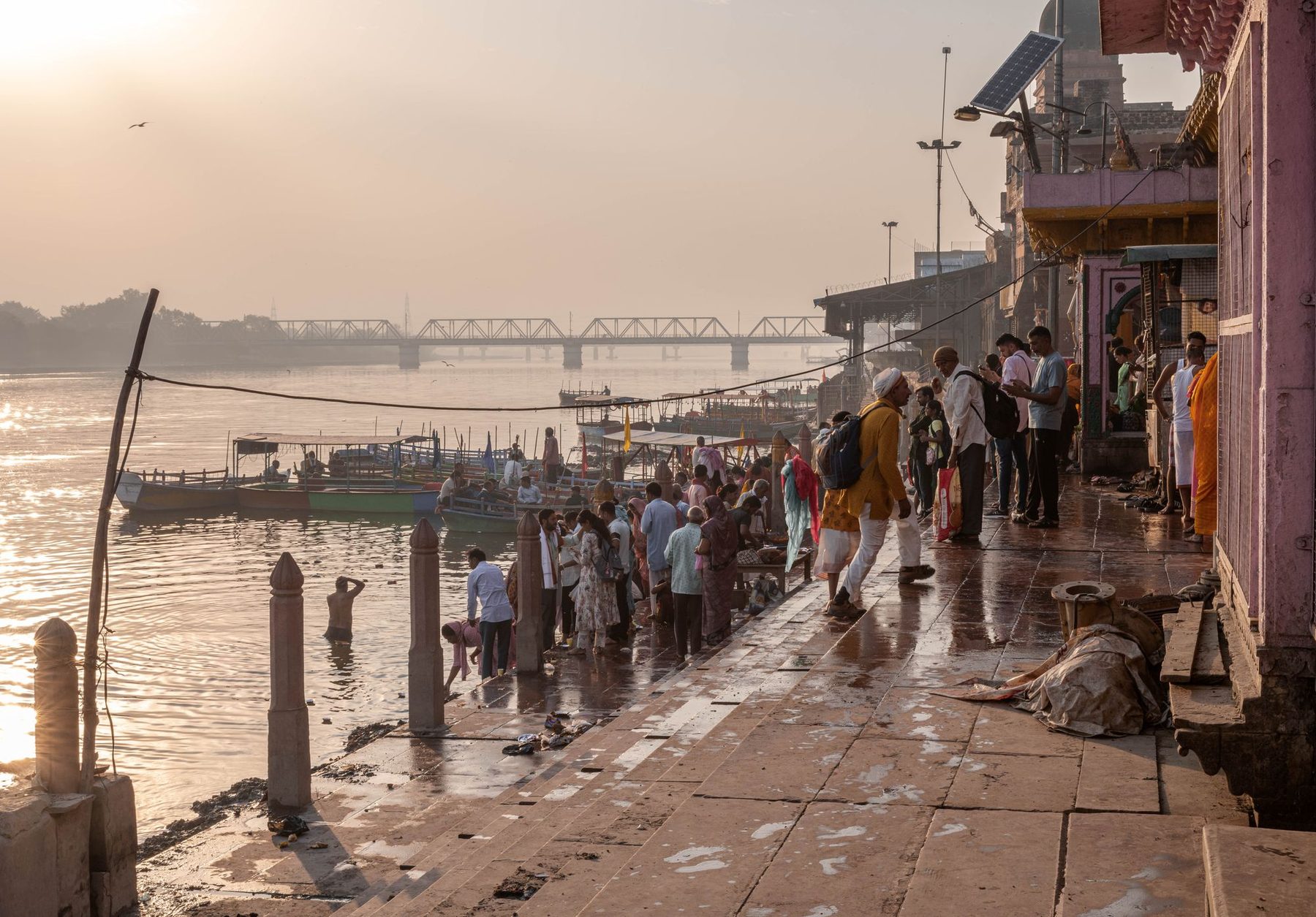 Mathura's ghats on the Yamuna at sunrise, with bathers and boats at the steps