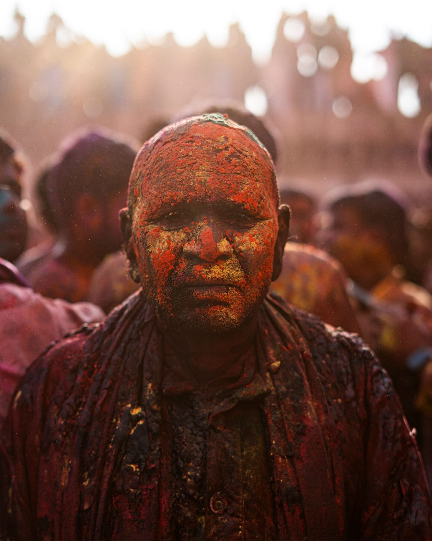 A man in Nandgaon covered in pink and orange powder during Holi