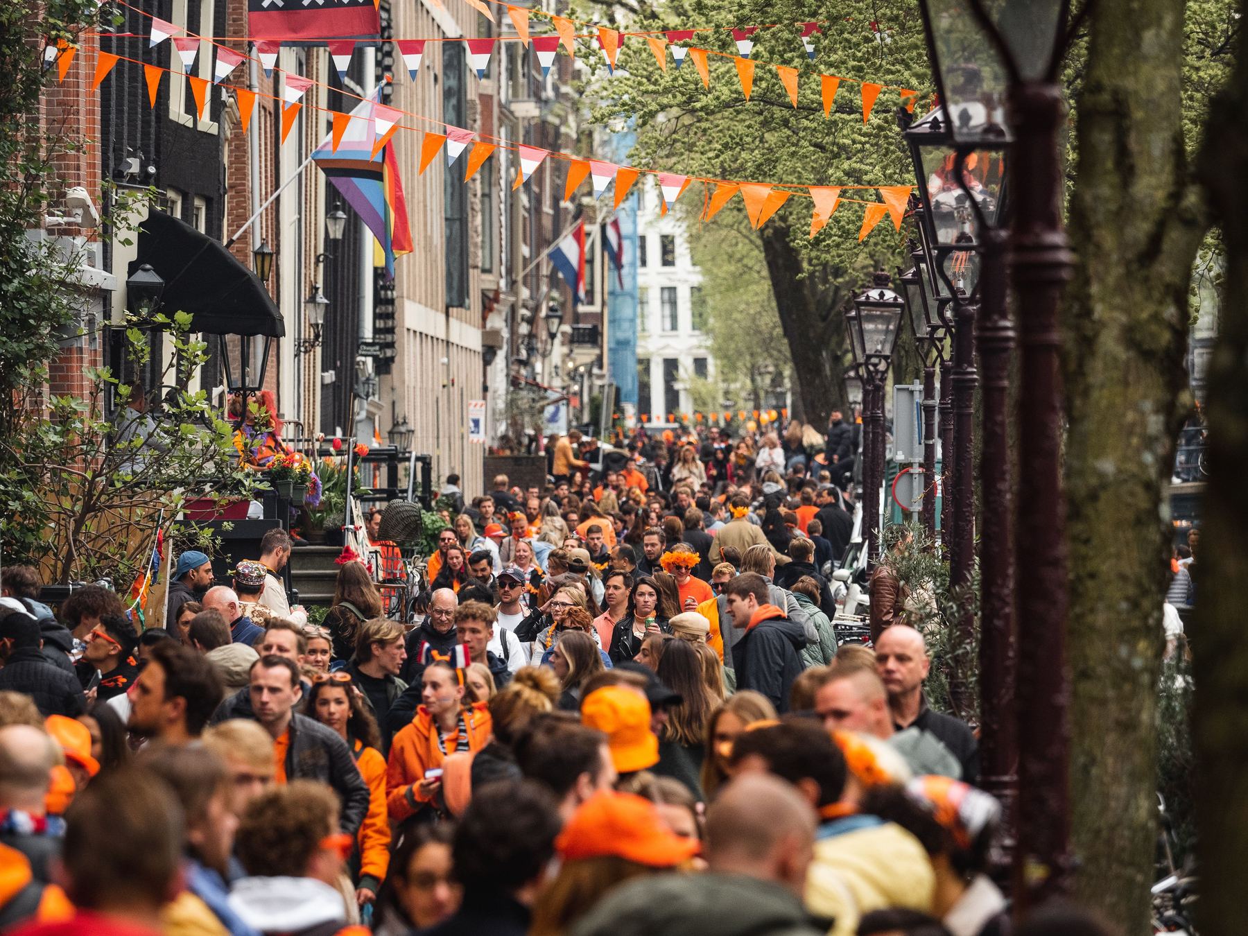 A street in Amsterdam hung with orange bunting and packed with people in orange on King's Day
