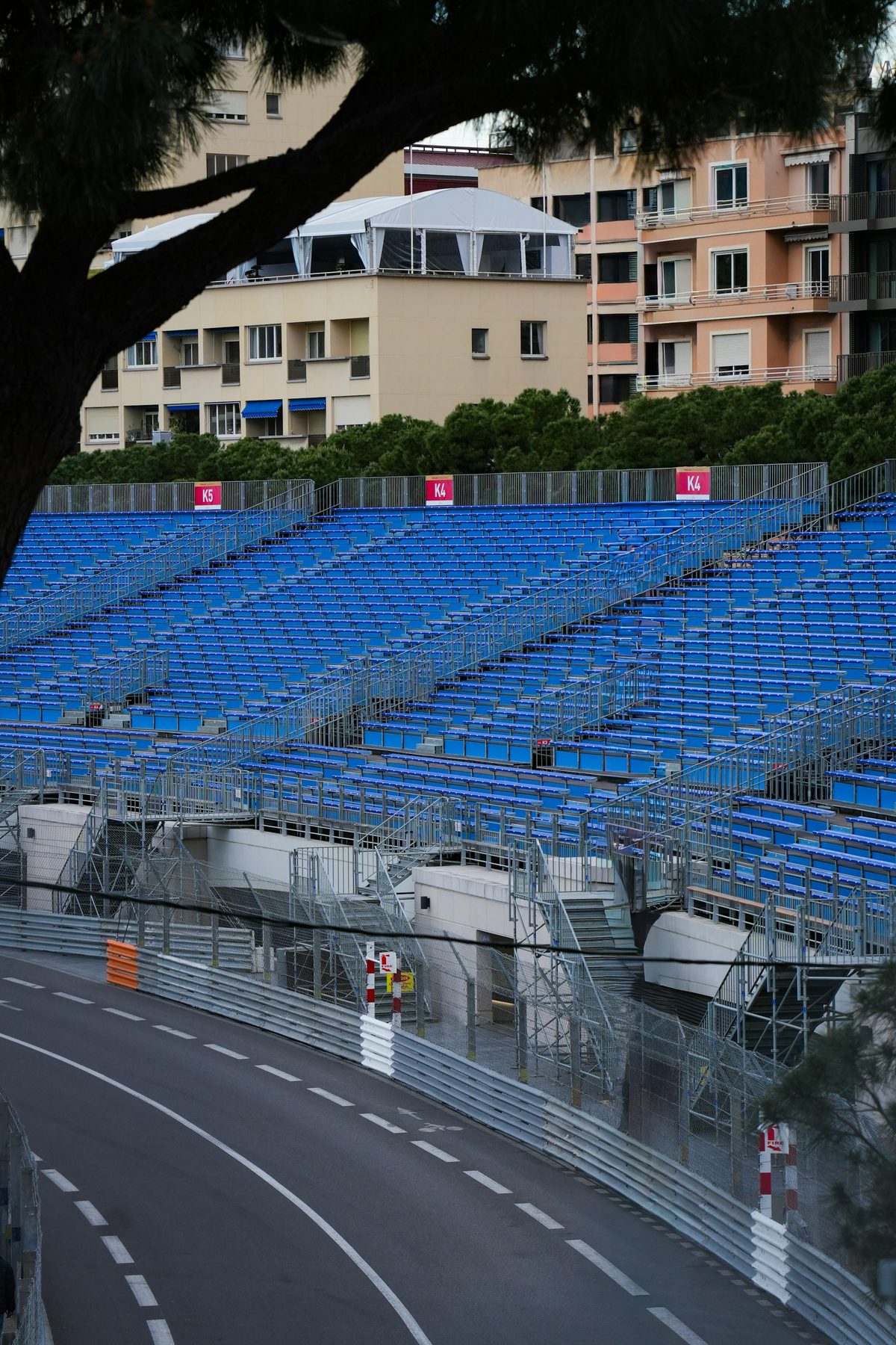 An empty blue grandstand above the Monaco circuit before the gates open, the track and barriers below