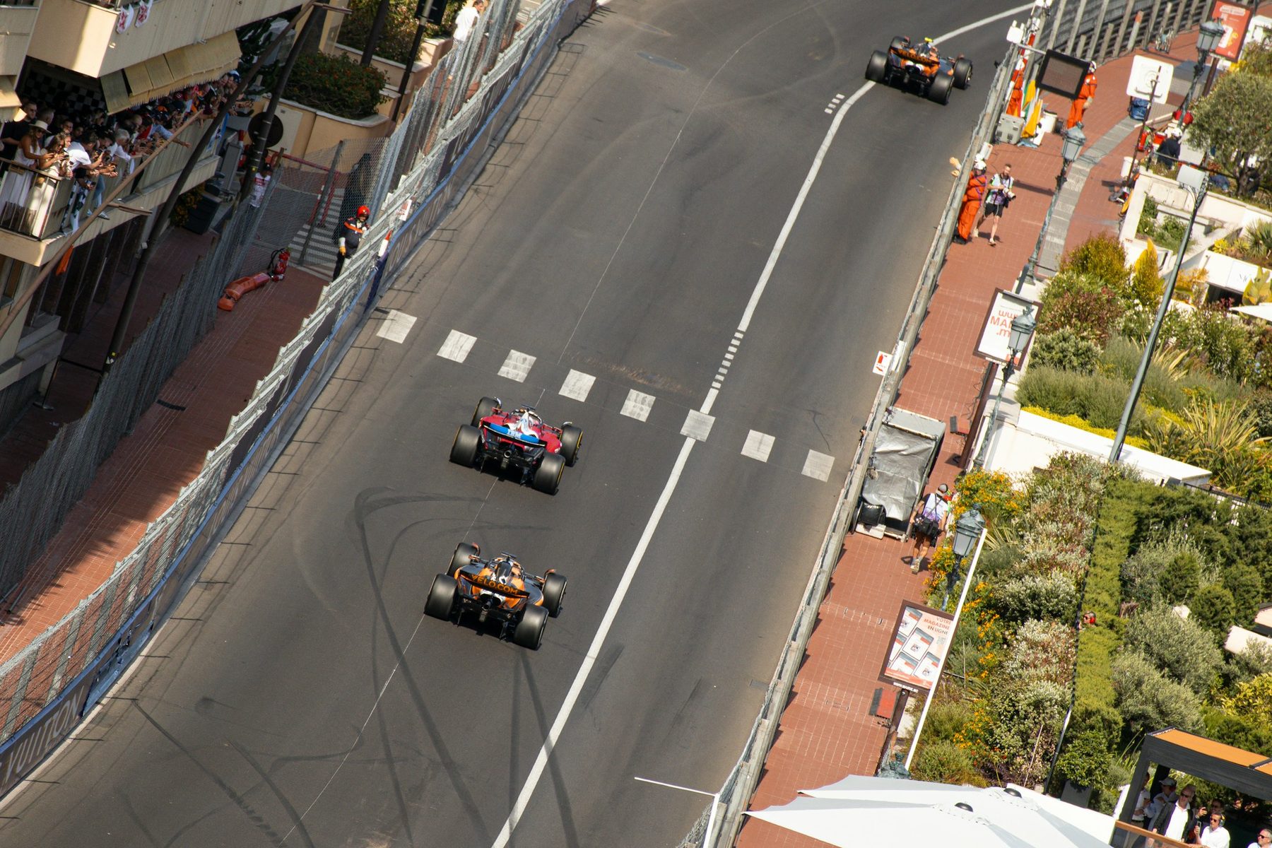 The start straight at Monaco from above, a Ferrari and a McLaren between the barriers with fans on the balconies