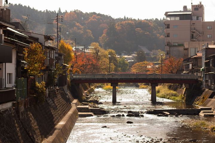 The Miyagawa river and the red Nakabashi bridge in Takayama in autumn