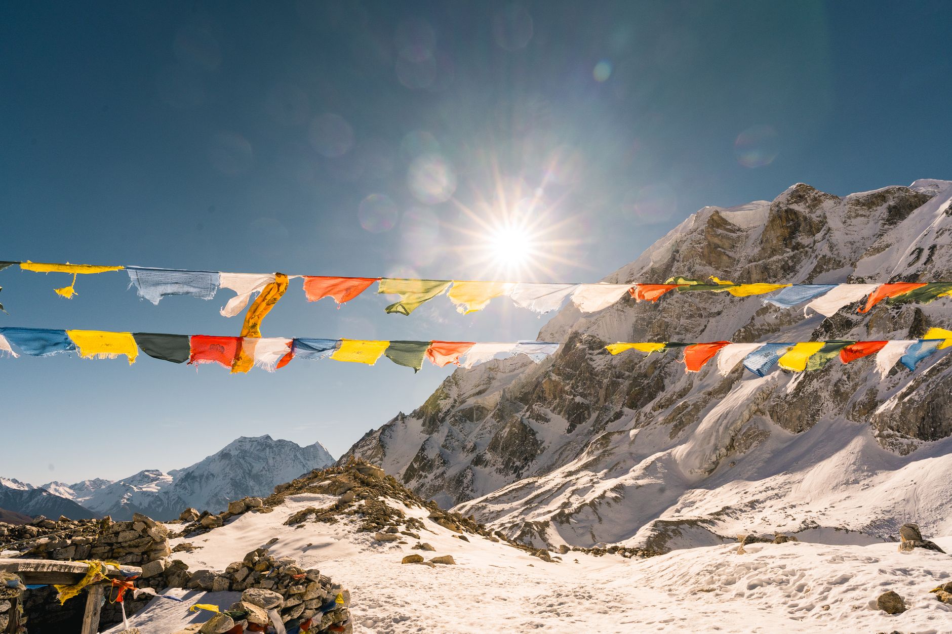 Prayer flags backlit by the sun above snow-covered rock high in the Khumbu