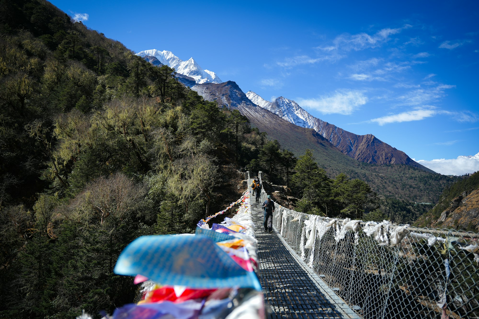 A steel suspension bridge hung with prayer flags crossing a gorge on the trail to Everest Base Camp