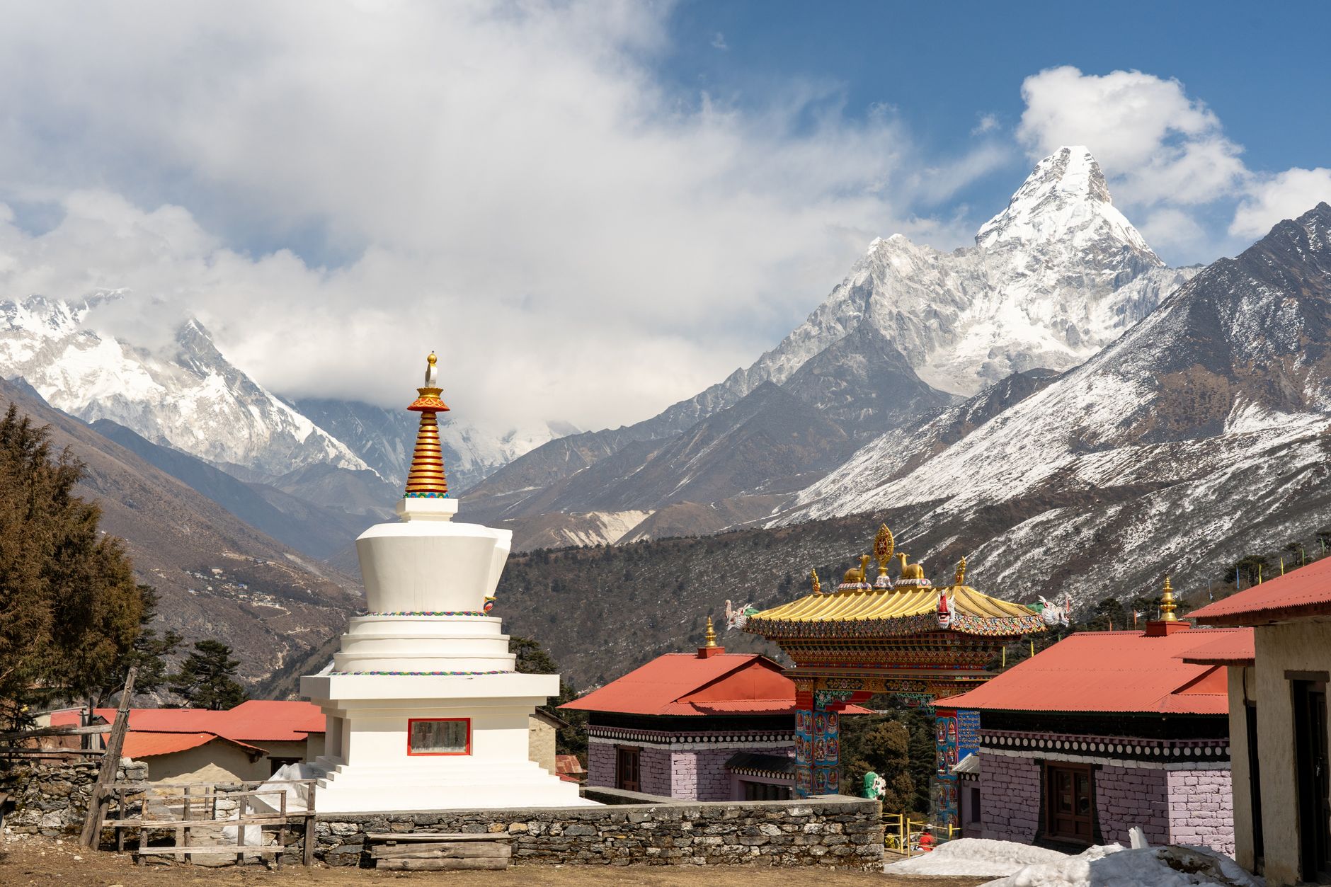 A whitewashed stupa and monastery buildings below Himalayan peaks at Tengboche