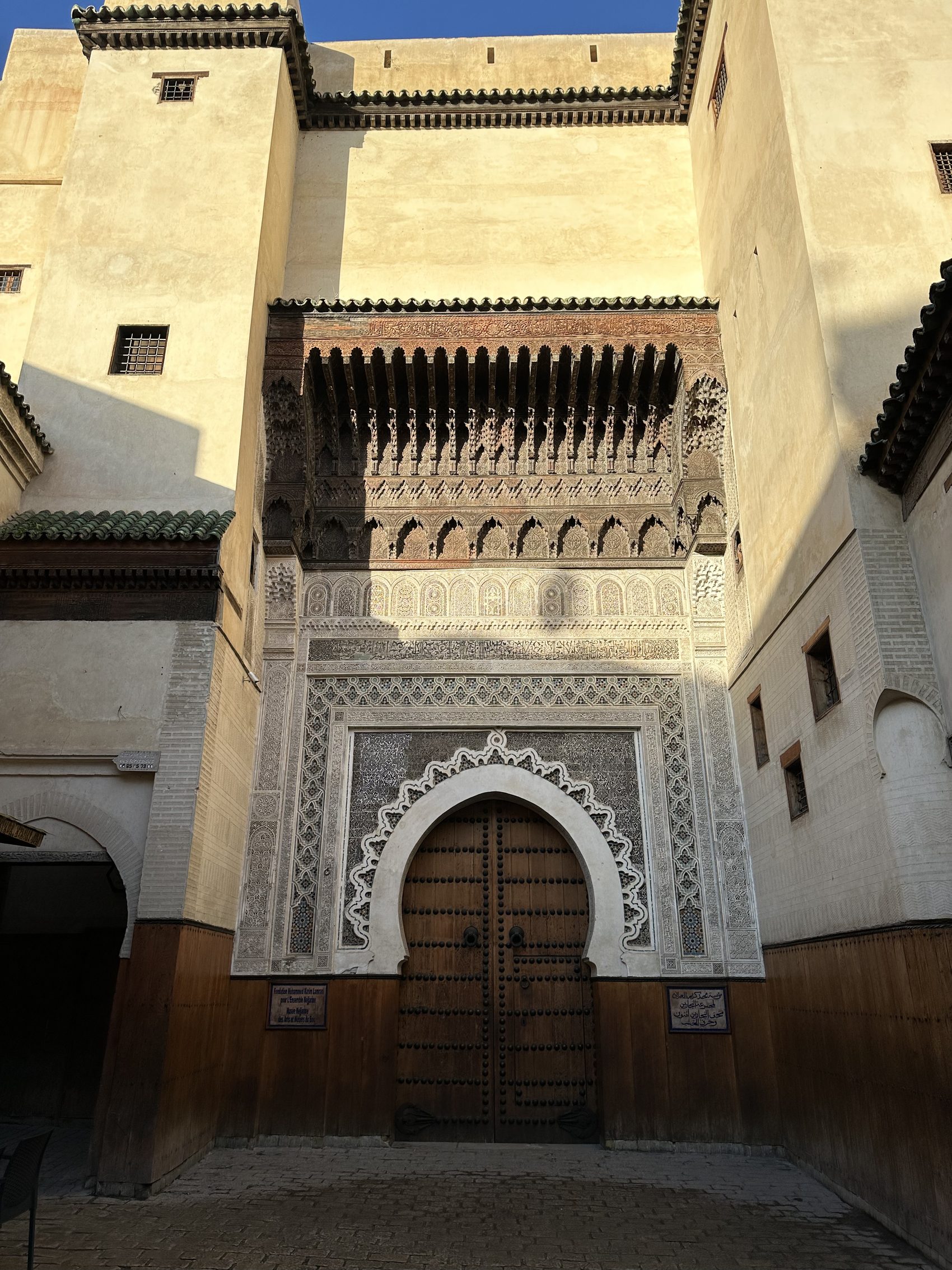 An ornate studded cedar door set in a plain wall in the Fez medina