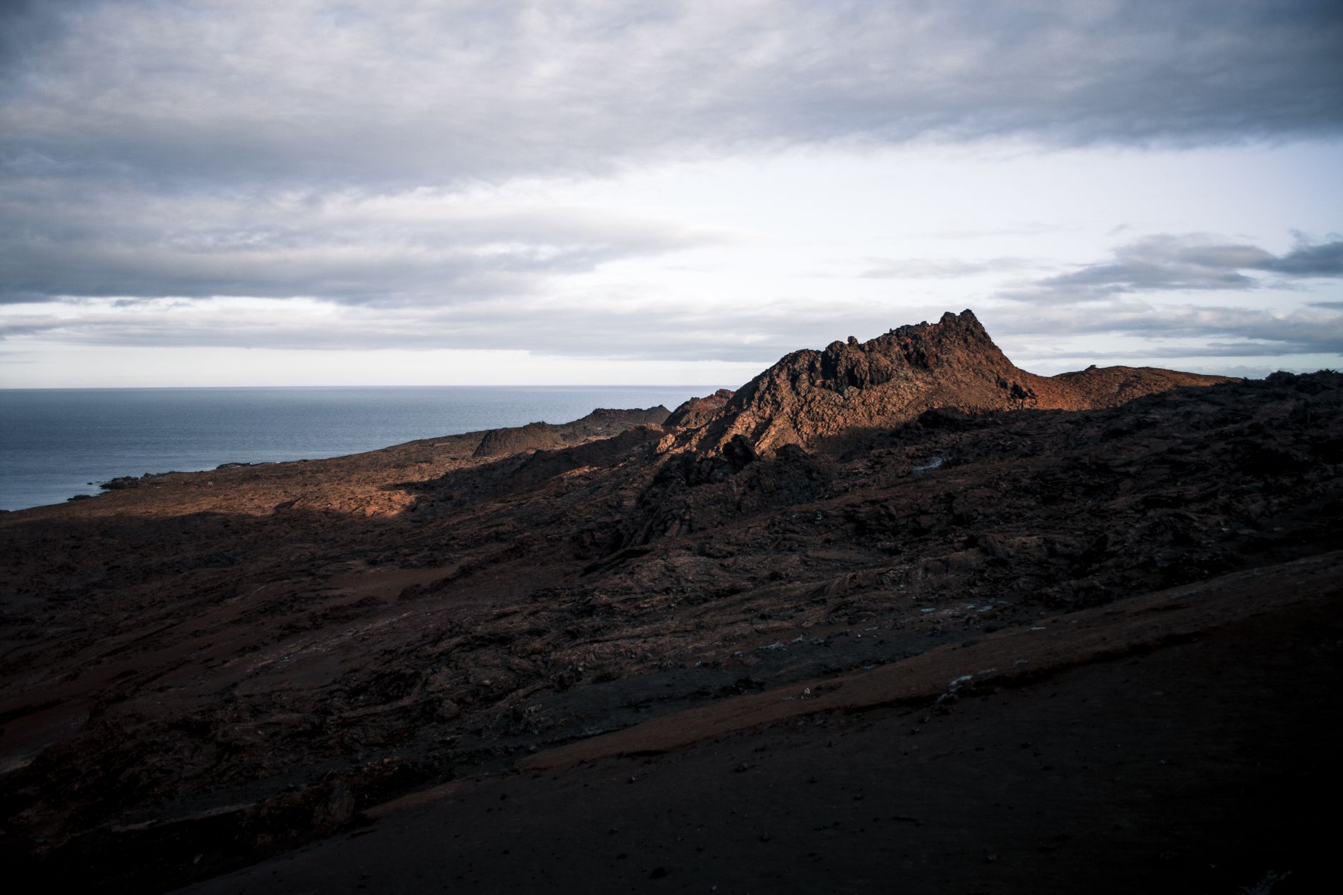 Bare volcanic terrain running down to the ocean in the Galapagos at sunset