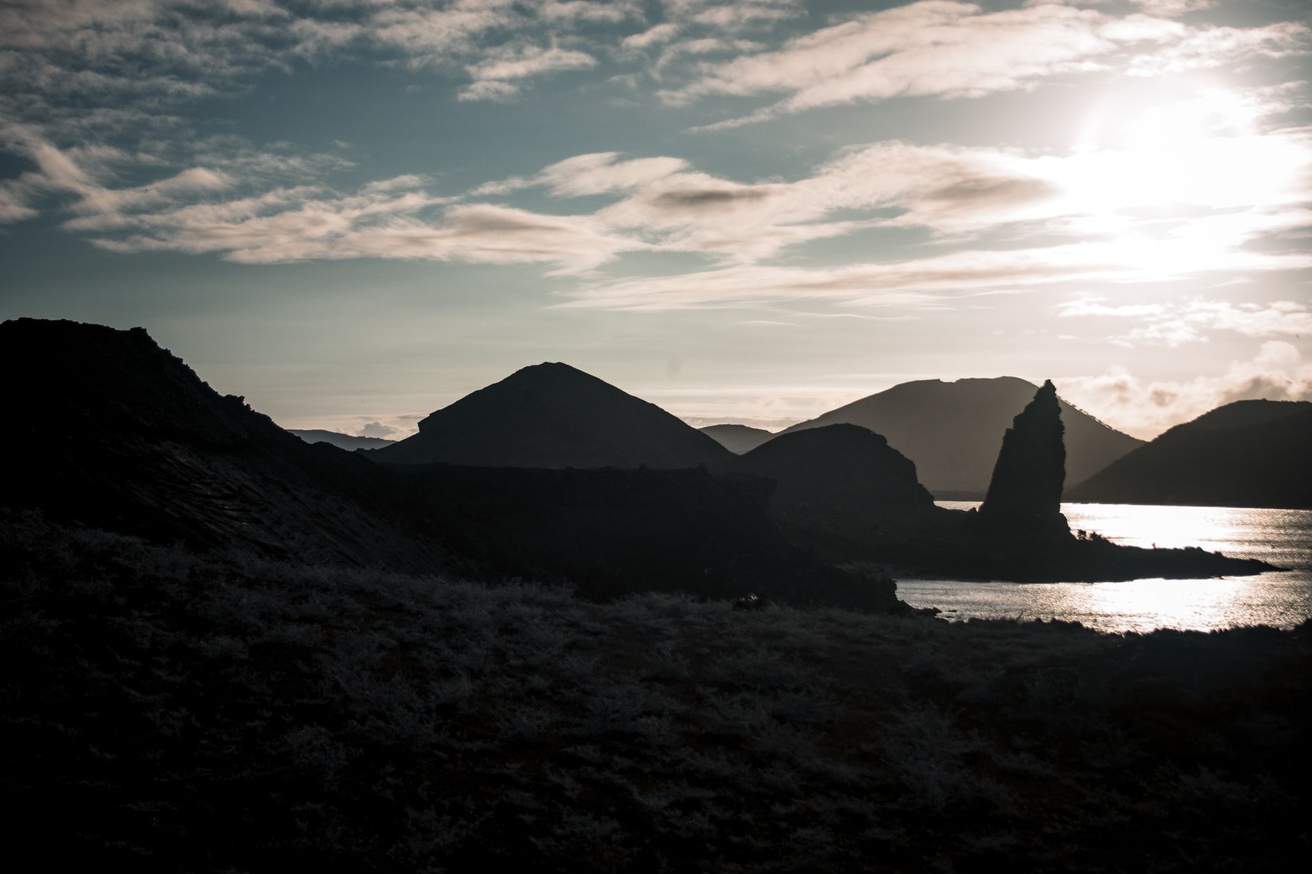 Pinnacle Rock and the volcanic cones of Bartolome Island silhouetted at sunset