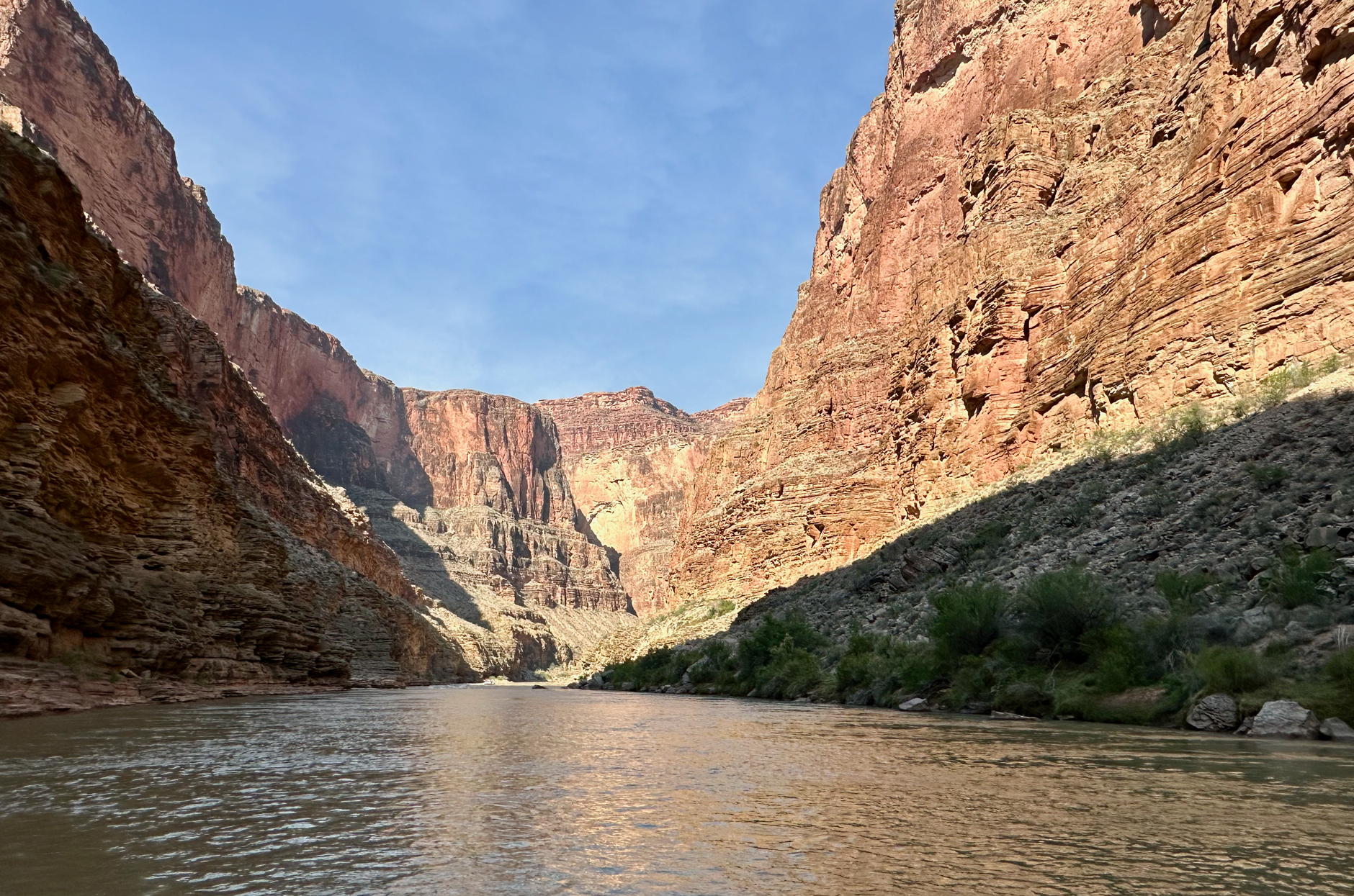 The Colorado running silt-heavy between the red walls of the Grand Canyon, seen from river level