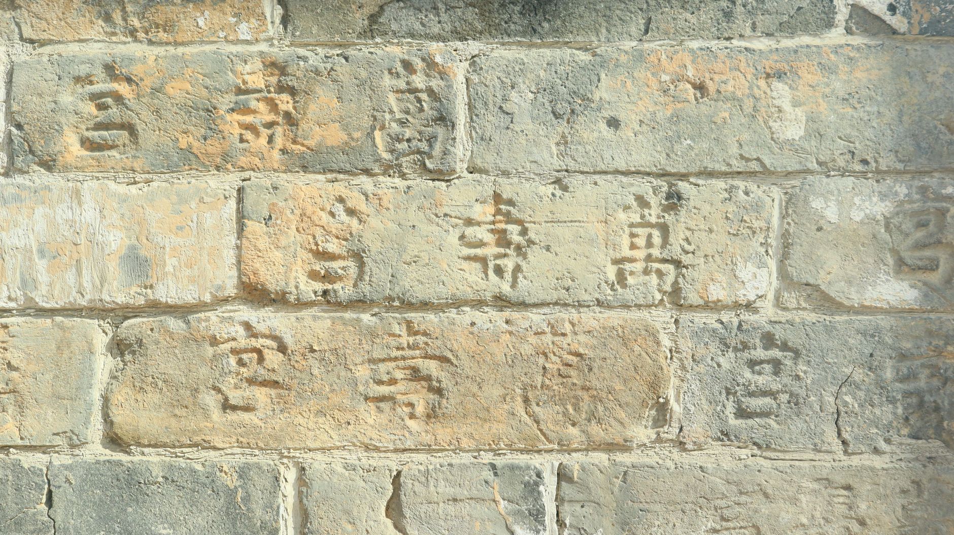 Chinese characters inscribed into the stone of an old wall