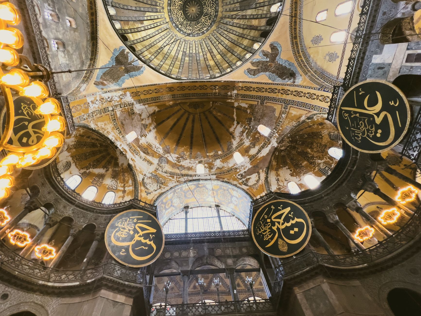 The vast interior of Hagia Sophia looking up into the great dome, chandeliers hanging low over the nave